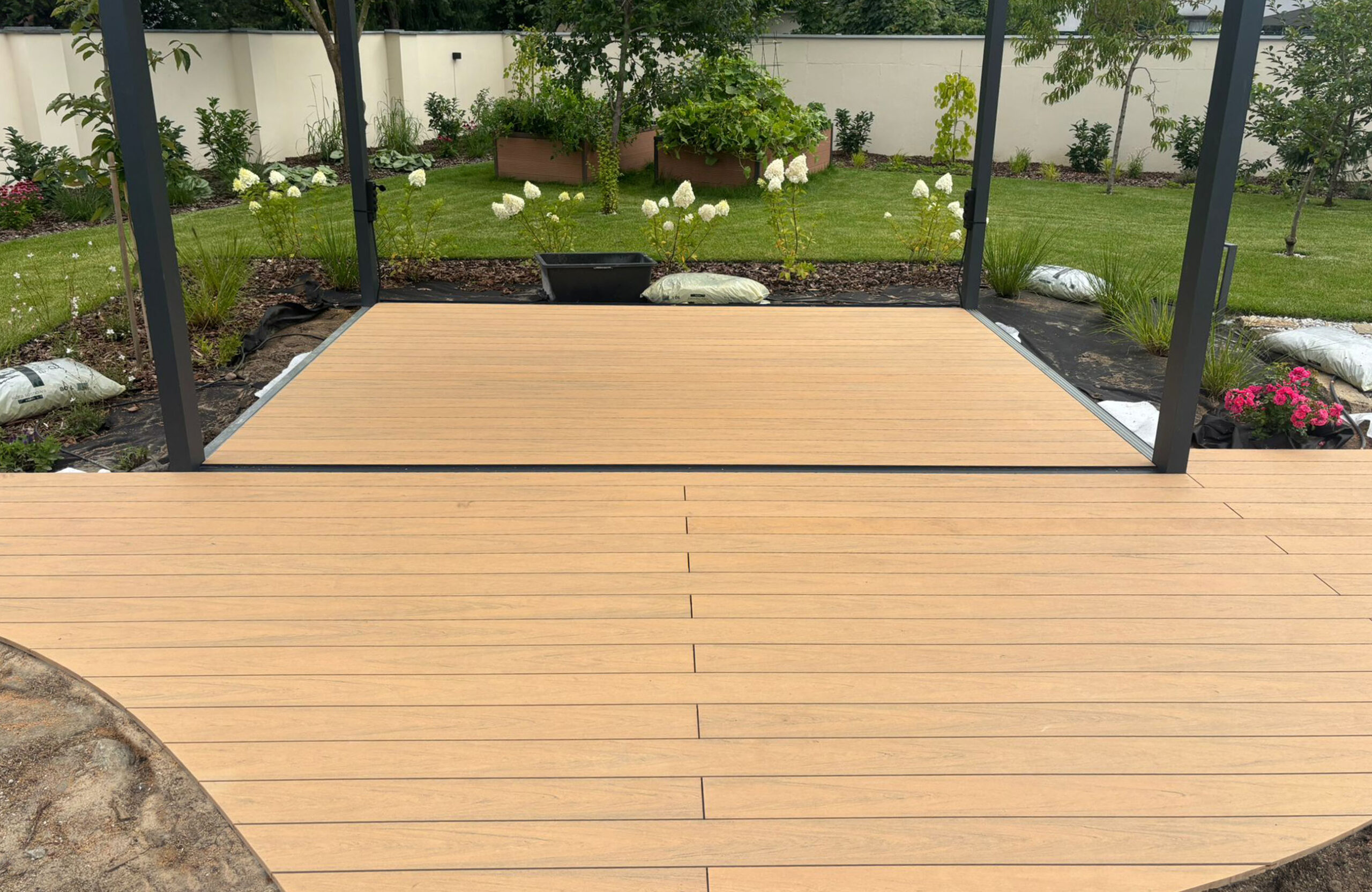 BRUGGAN Multicolor sand decking with a custom curved design beside a landscaped garden pond