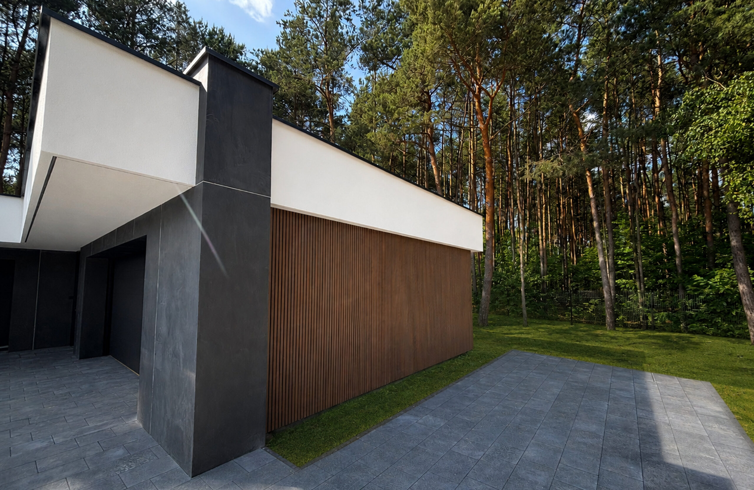 Modern house exterior with white and dark gray walls, wood-clad siding, and a backdrop of tall pine trees on a sunny day.