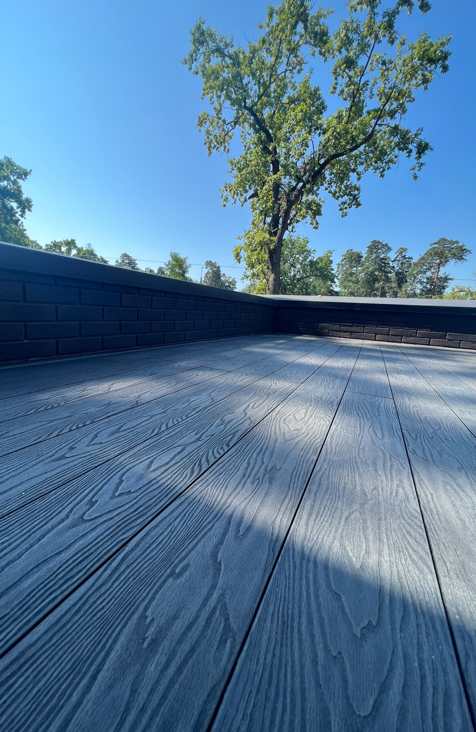 Anthracite composite decking on a modern terrace surrounded by mature trees