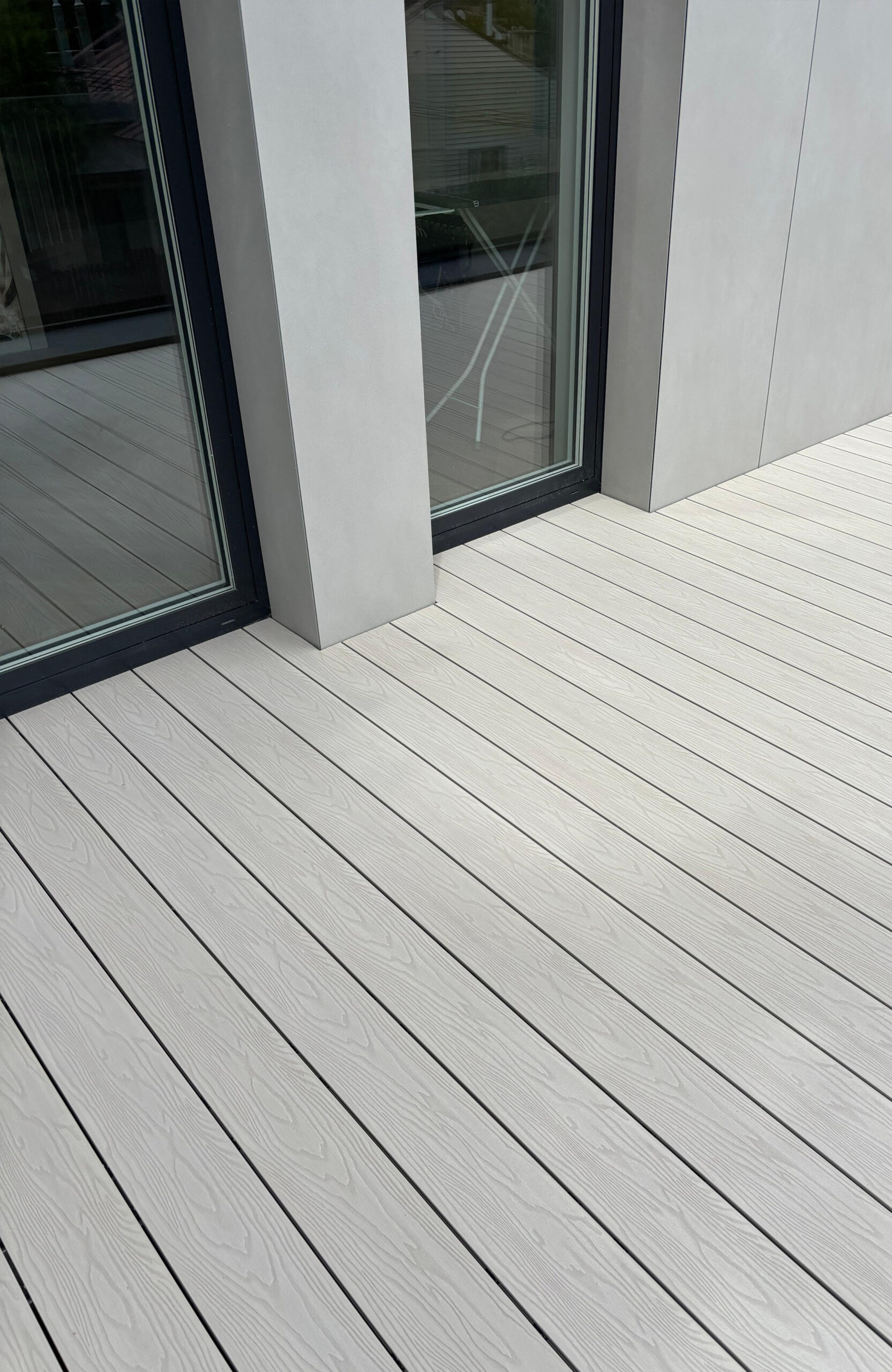 Light composite decking around a modern house with floor-to-ceiling windows