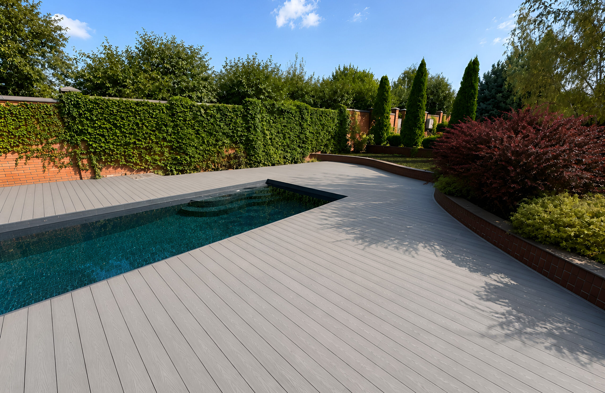 Bruggan Elegant Graphite composite decking around a modern swimming pool in a landscaped garden