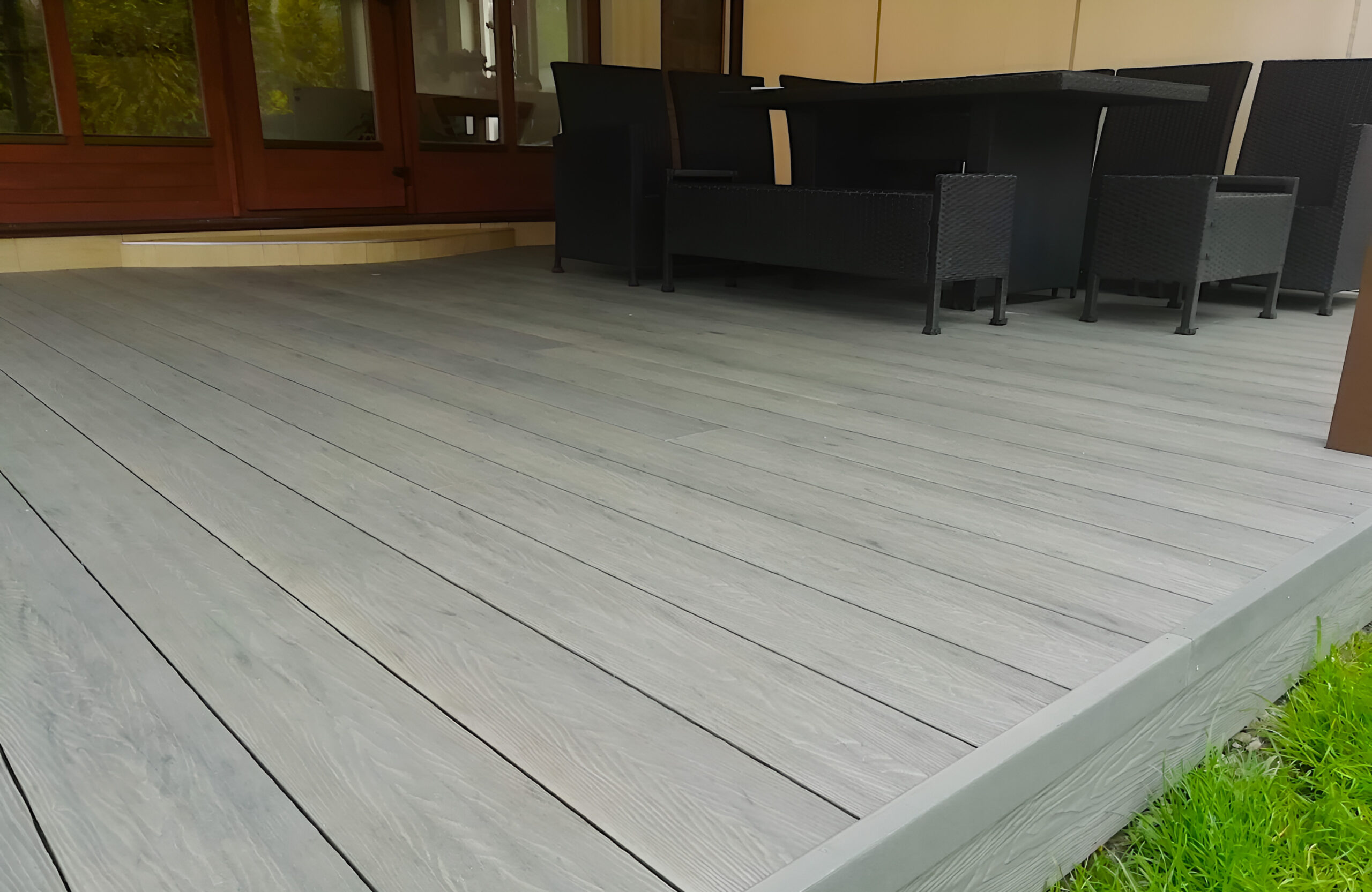 Bruggan Elegant Graphite composite decking on a covered outdoor terrace with dining furniture