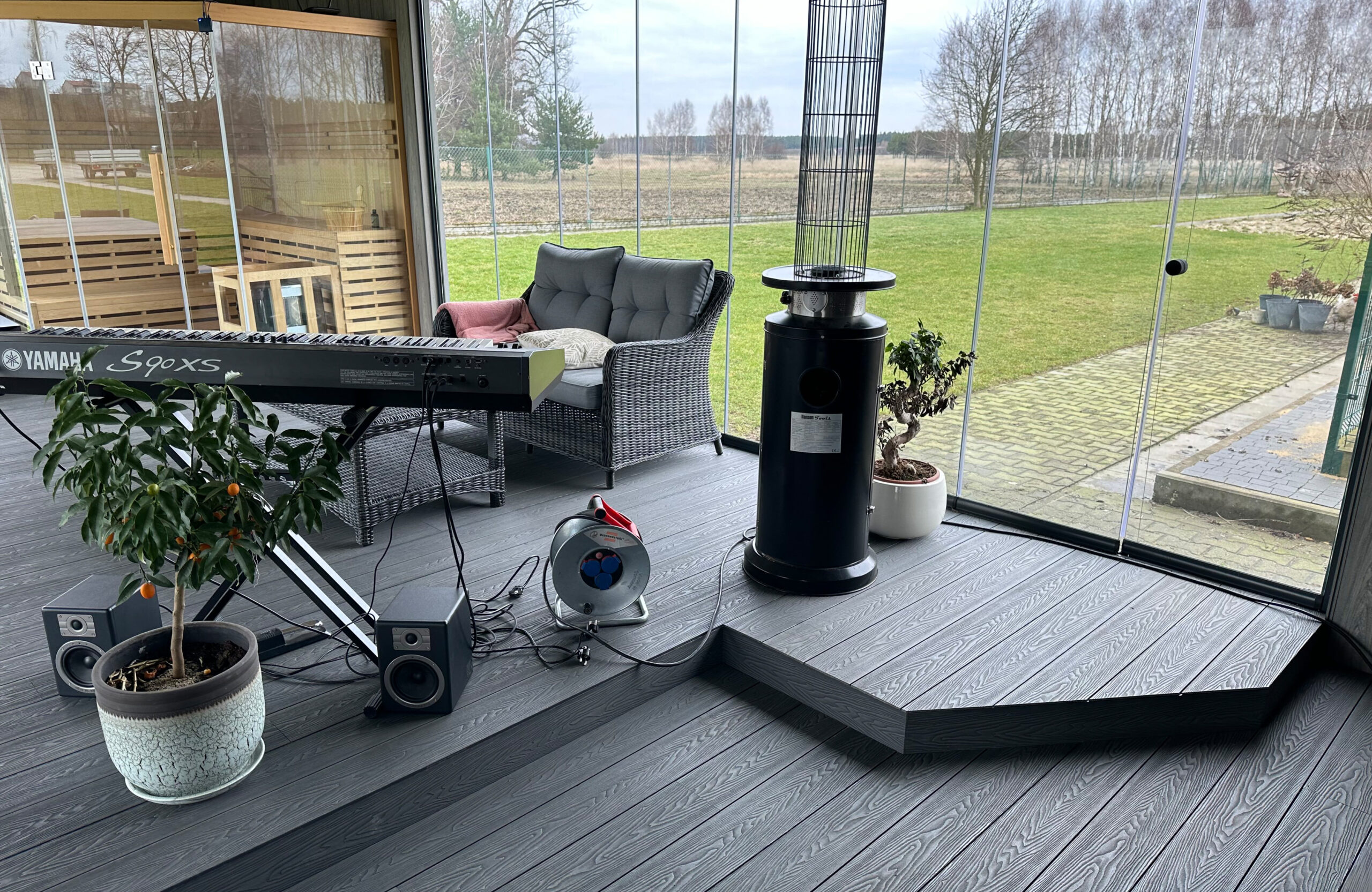 Bruggan Elegant Graphite composite decking in a glass-enclosed terrace with outdoor furniture