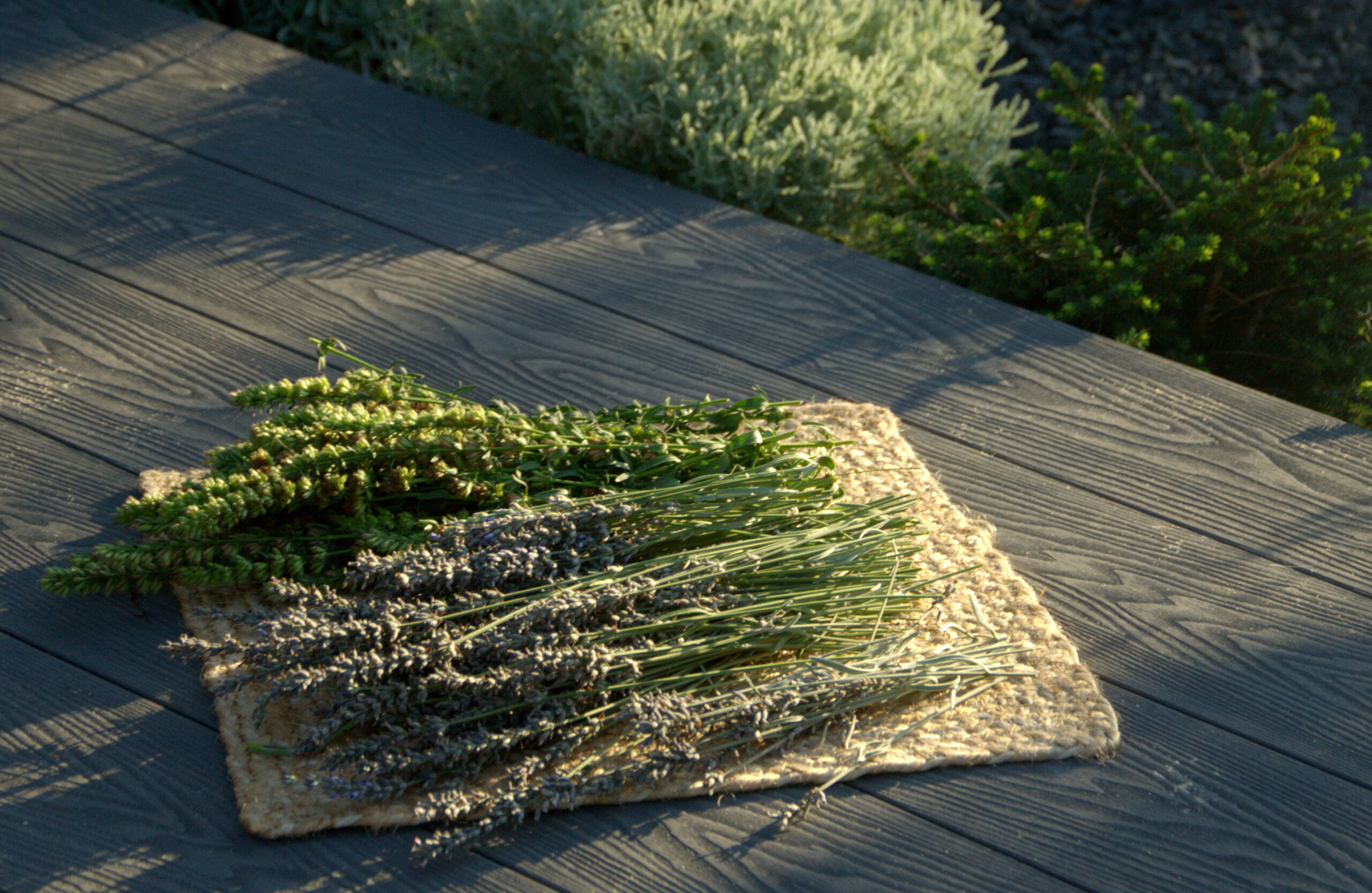 Bruggan Elegant Graphite composite decking with natural wood grain texture and fresh herbs in a garden setting