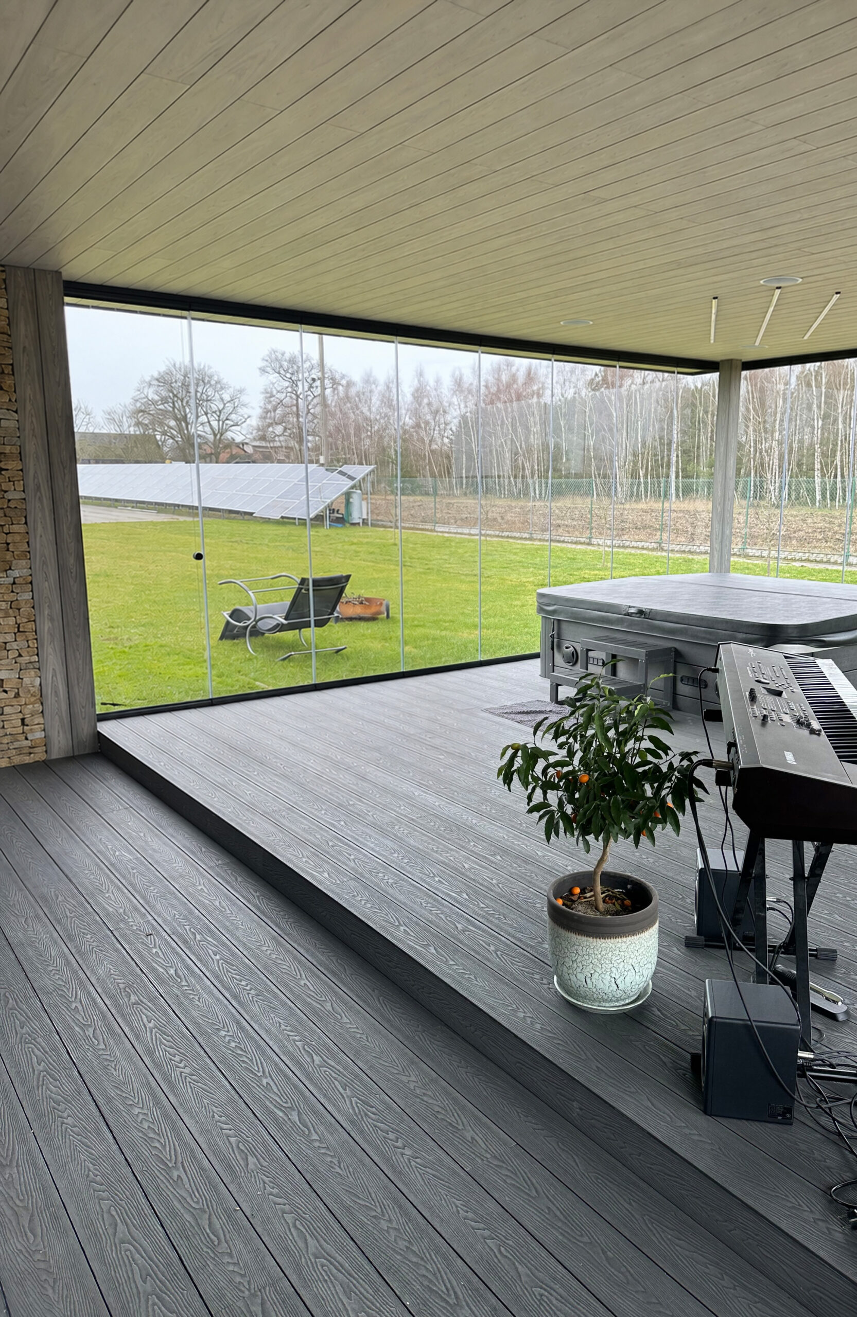 Spacious covered terrace with Bruggan Elegant Graphite decking, glass walls and hot tub