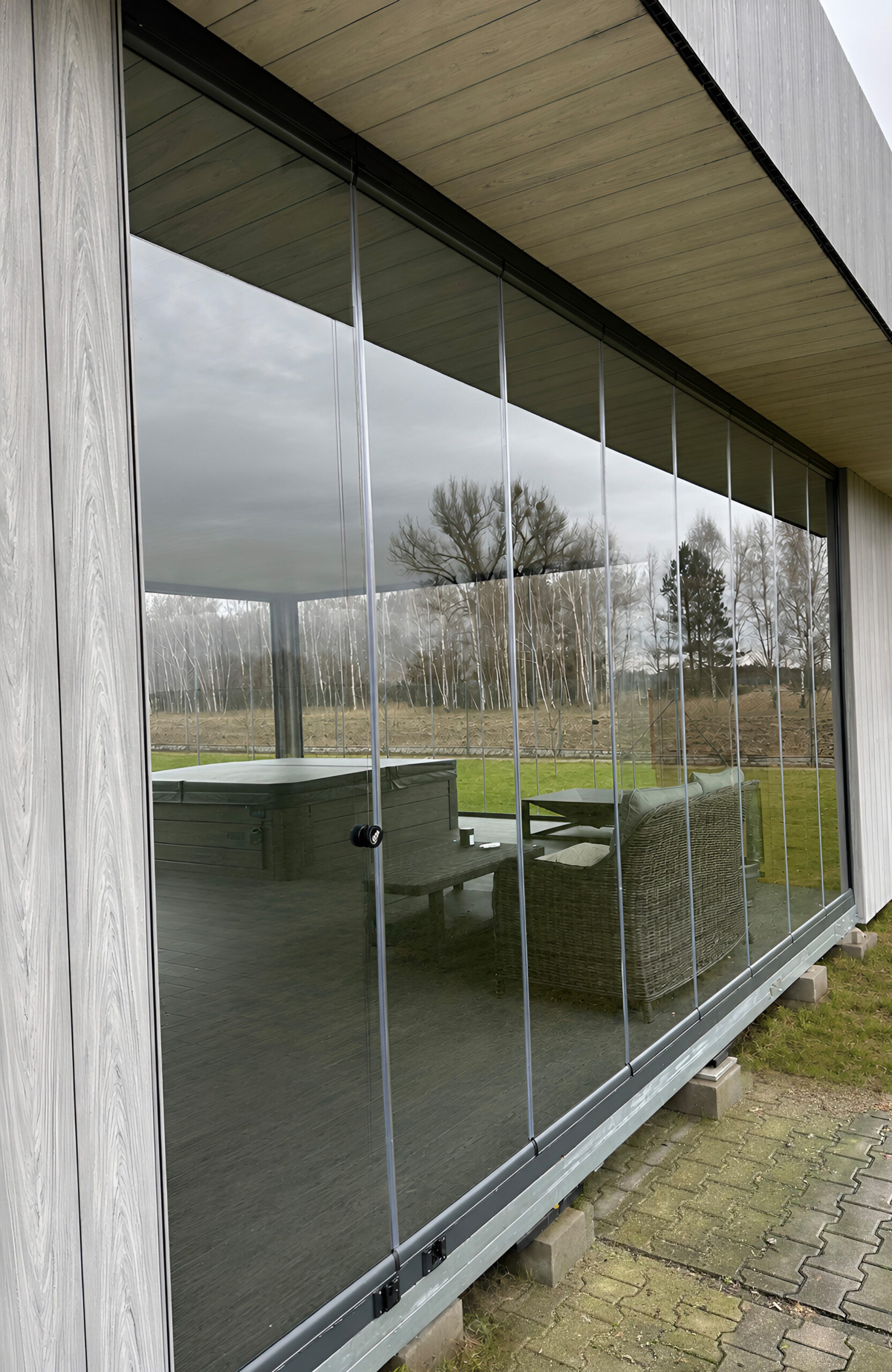 Exterior view of a glass-enclosed terrace finished with Bruggan Elegant Graphite composite decking