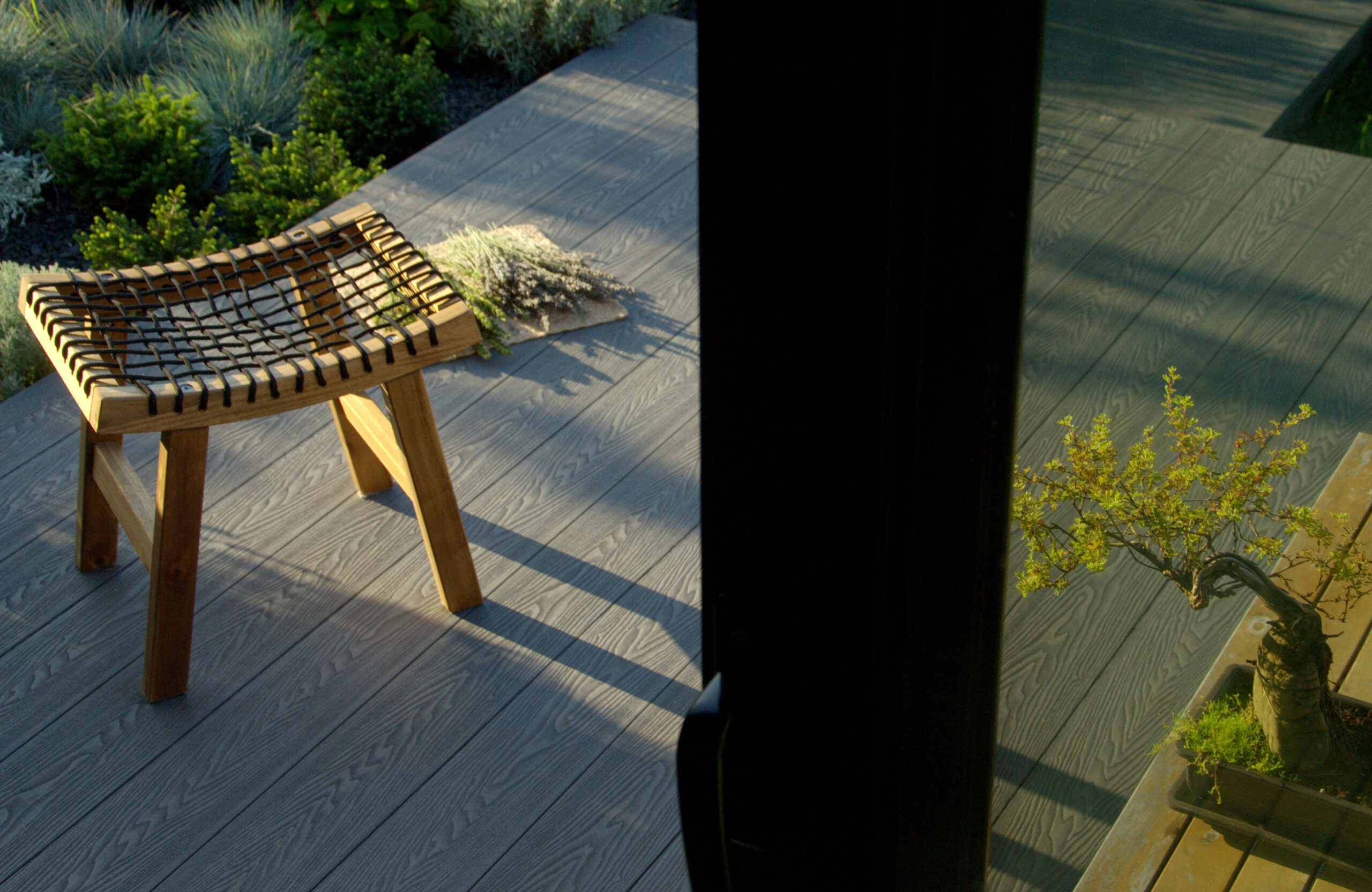 Graphite composite decking terrace with wooden outdoor furniture and landscaped garden