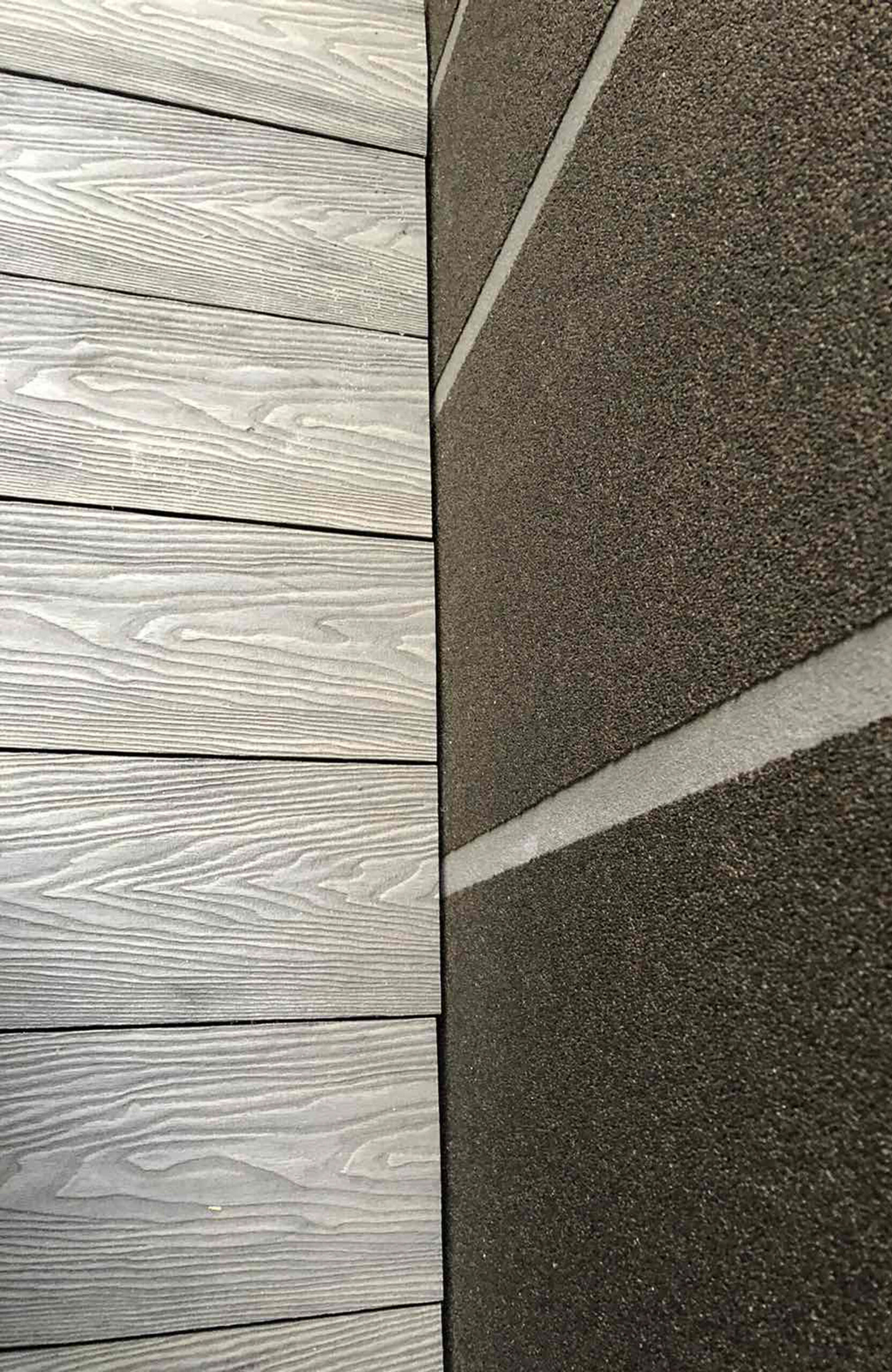 Close-up of Bruggan Elegant Graphite decking with realistic wood grain texture next to paving stones
