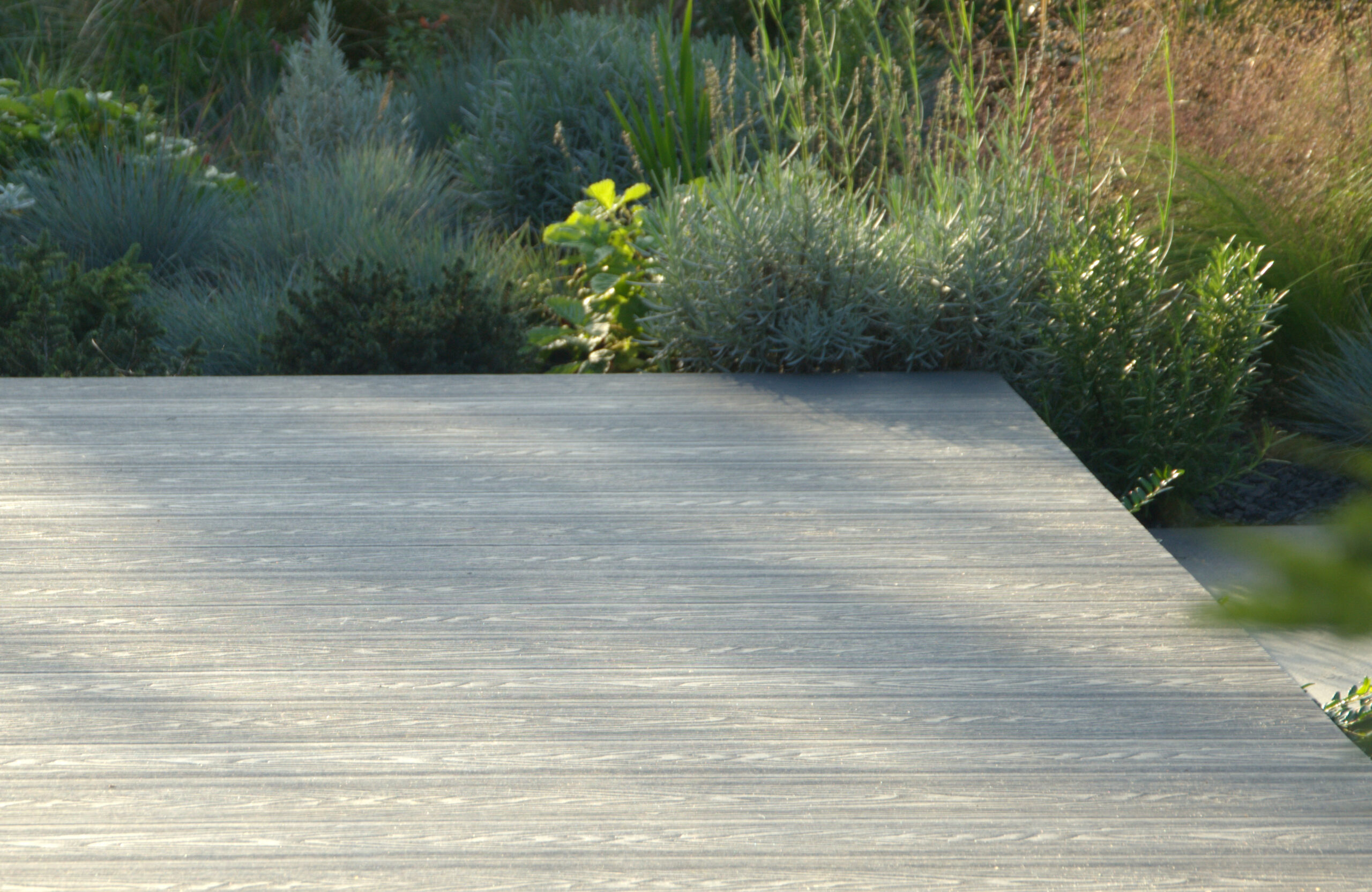 Graphite composite decking terrace with realistic wood grain texture in a landscaped garden