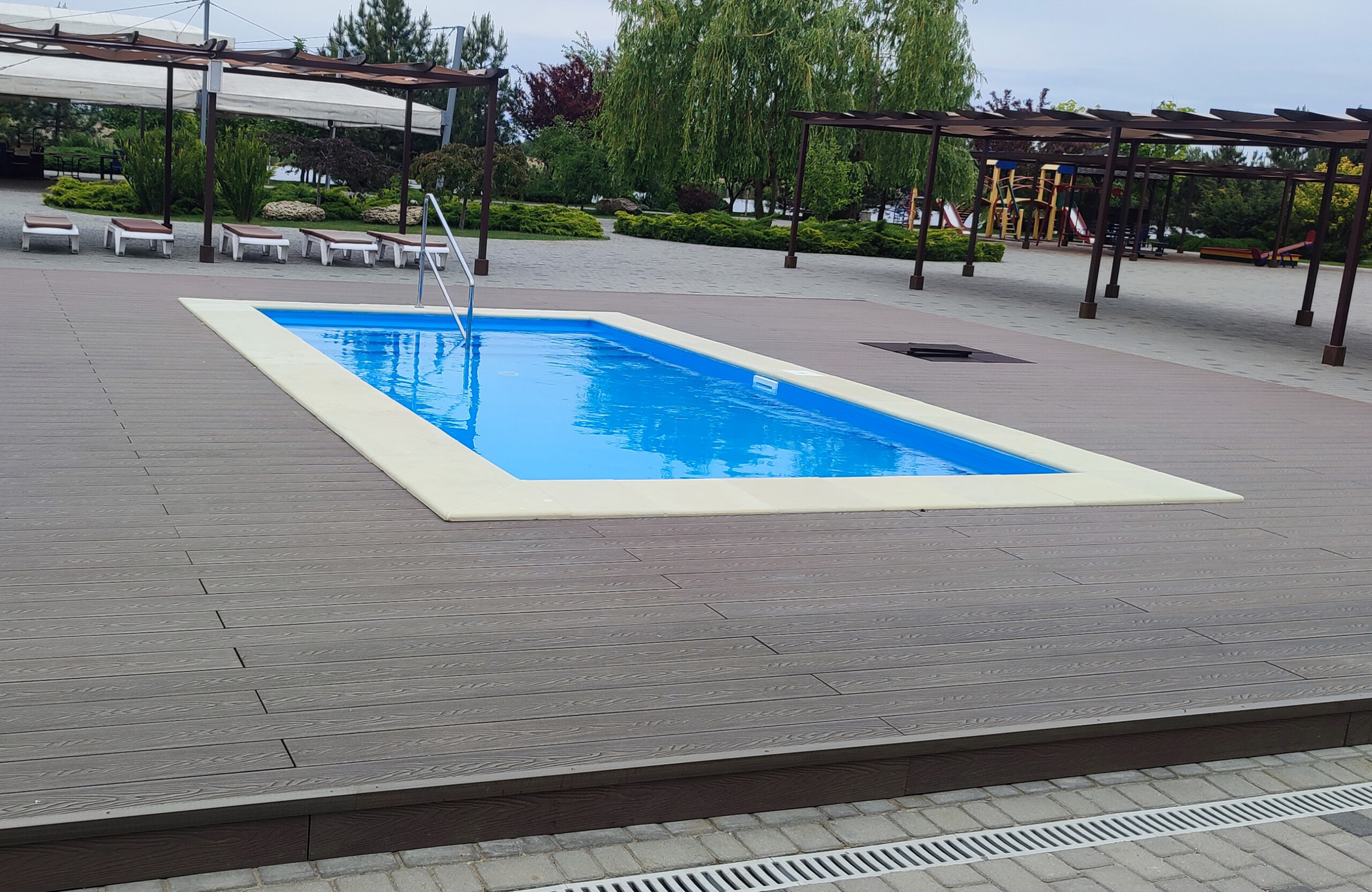 Bruggan Elegant Wine Brown composite decking around an outdoor swimming pool at Ostrov River Club, Dnipropetrovsk Oblast, Ukraine