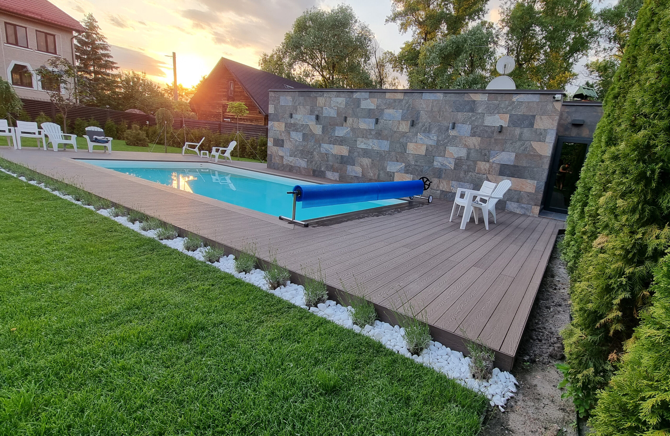 Bruggan Elegant Wine Brown composite decking around a private outdoor swimming pool with landscaped garden