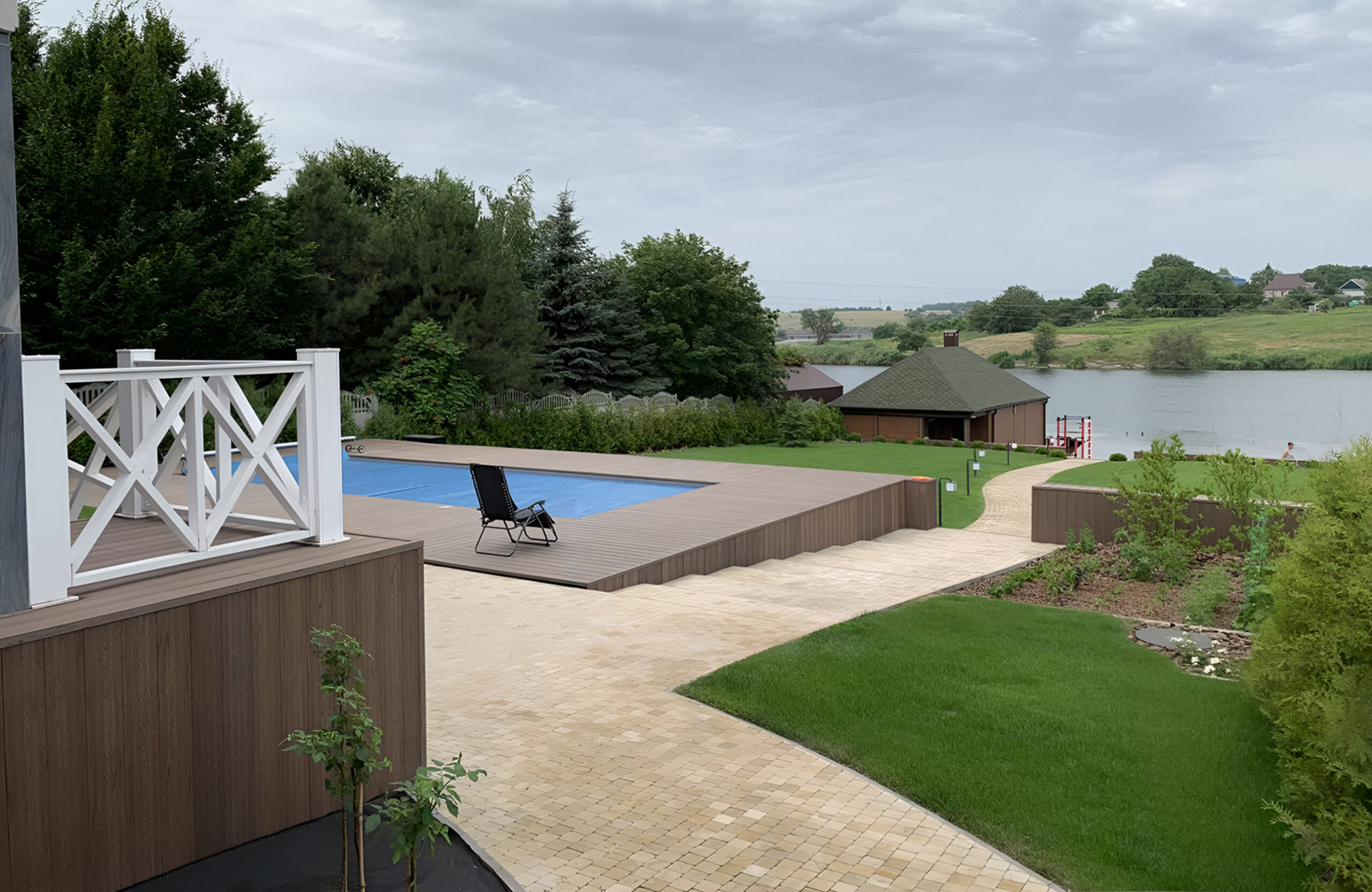 Bruggan Elegant Wine Brown composite decking around a private swimming pool overlooking a landscaped garden and lake