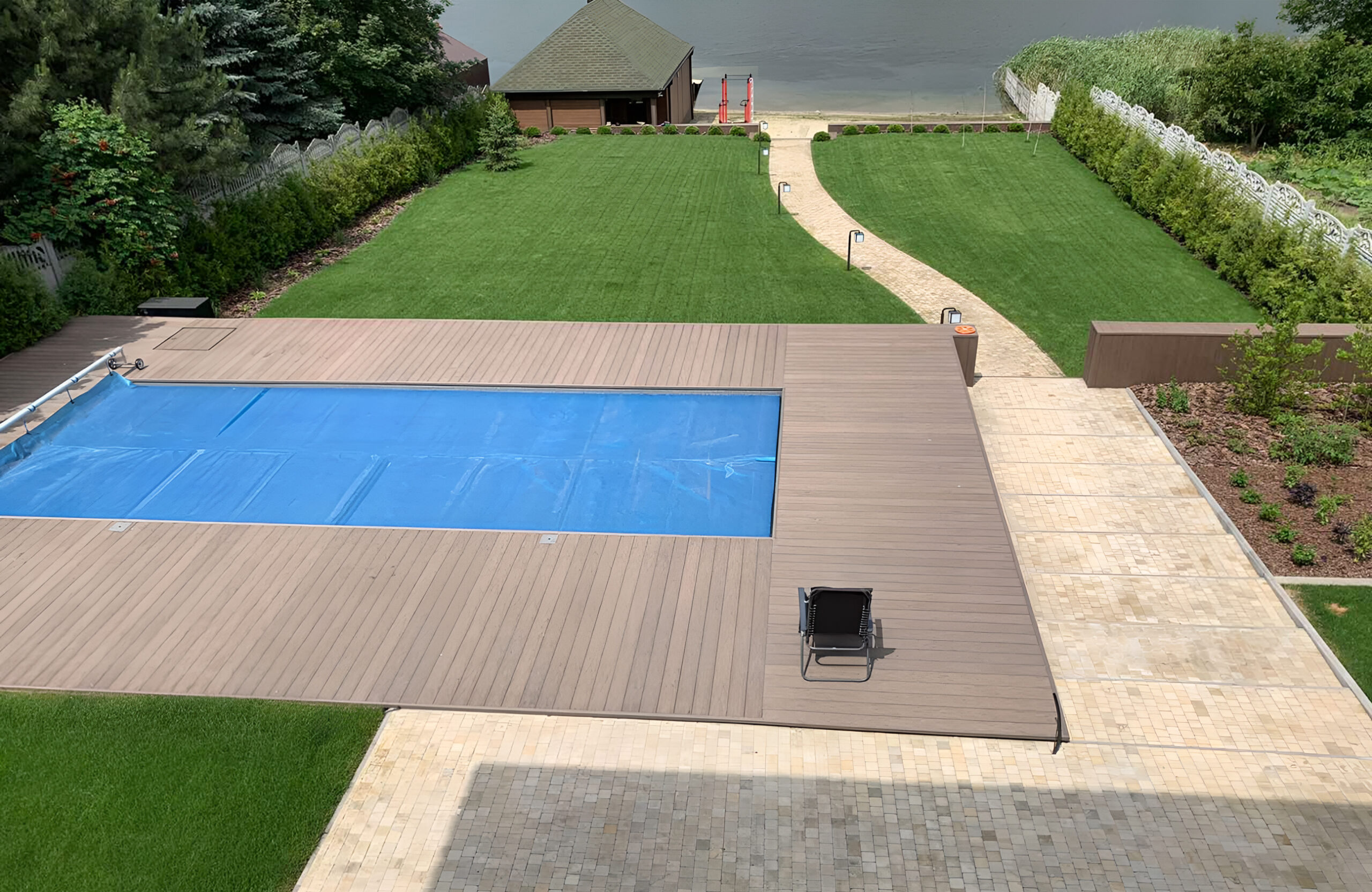 Bruggan Elegant Wine Brown pool deck with composite decking, green lawn and lakeside landscape