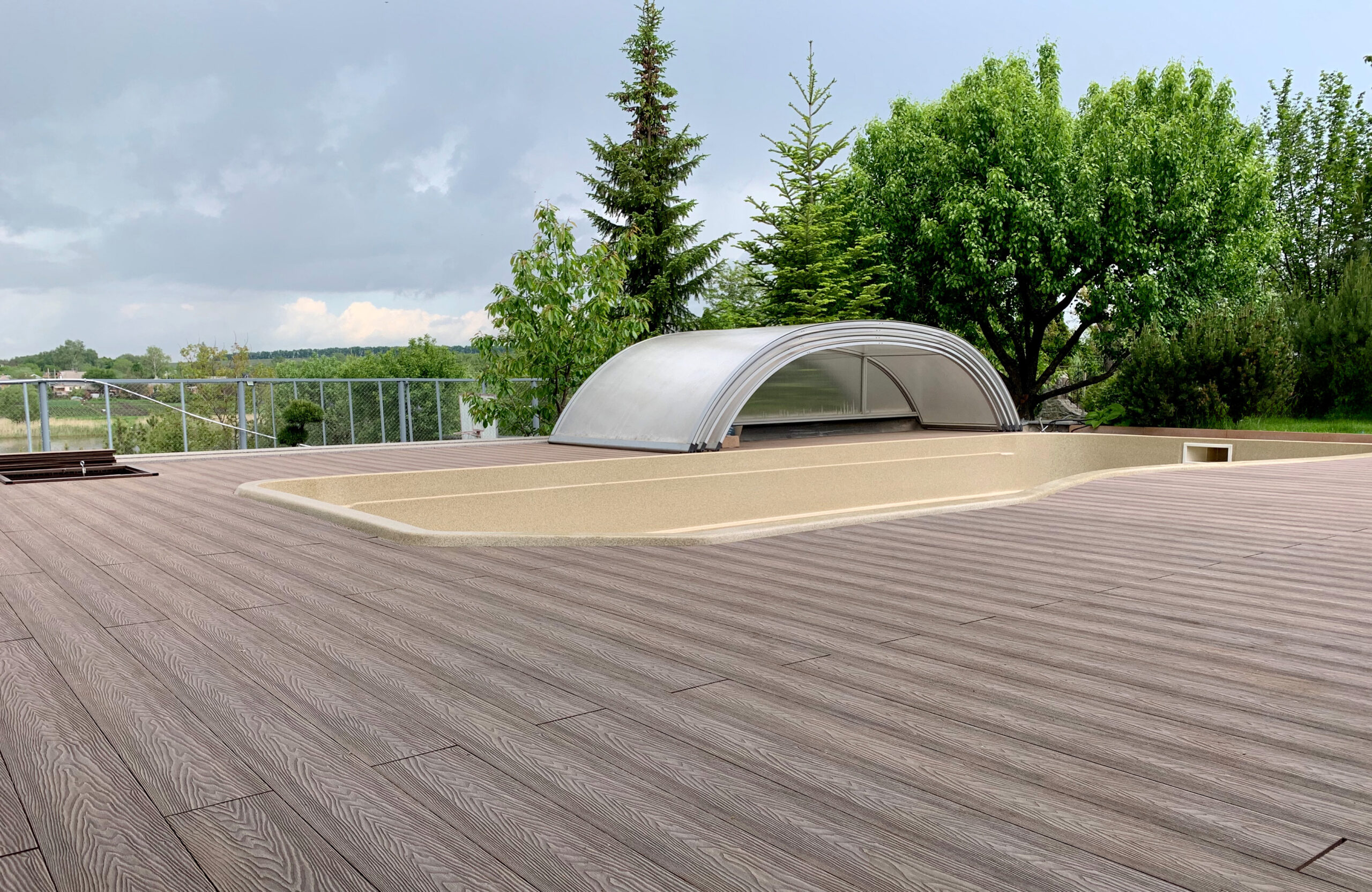 Close-up of Bruggan Elegant Wine Brown composite decking with natural wood grain texture beside a covered swimming pool