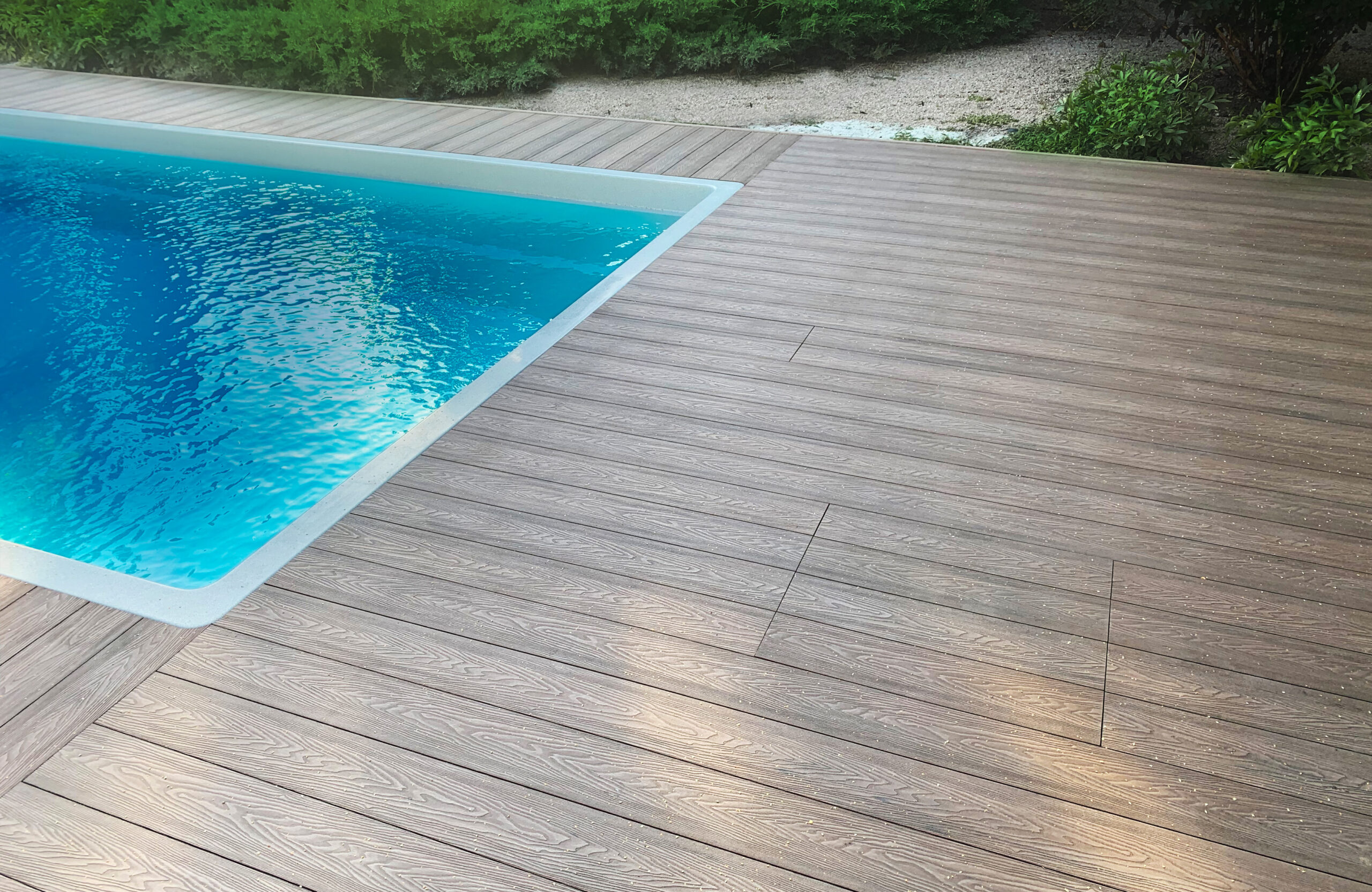 Bruggan Elegant Wine Brown composite decking with wood grain texture and integrated access panels beside a swimming pool