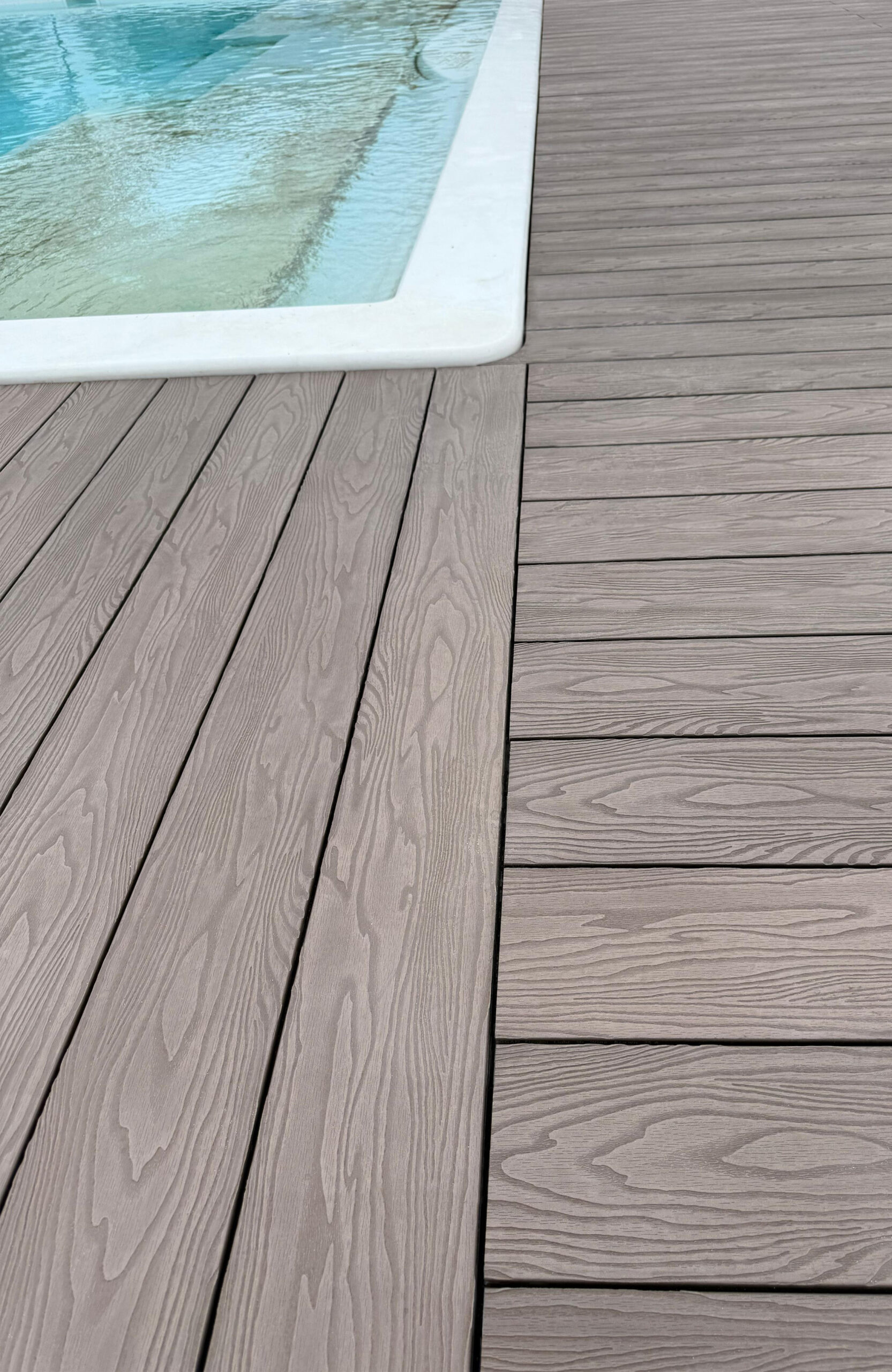 Close-up of Bruggan Elegant Wine Brown composite decking with natural wood grain beside the swimming pool