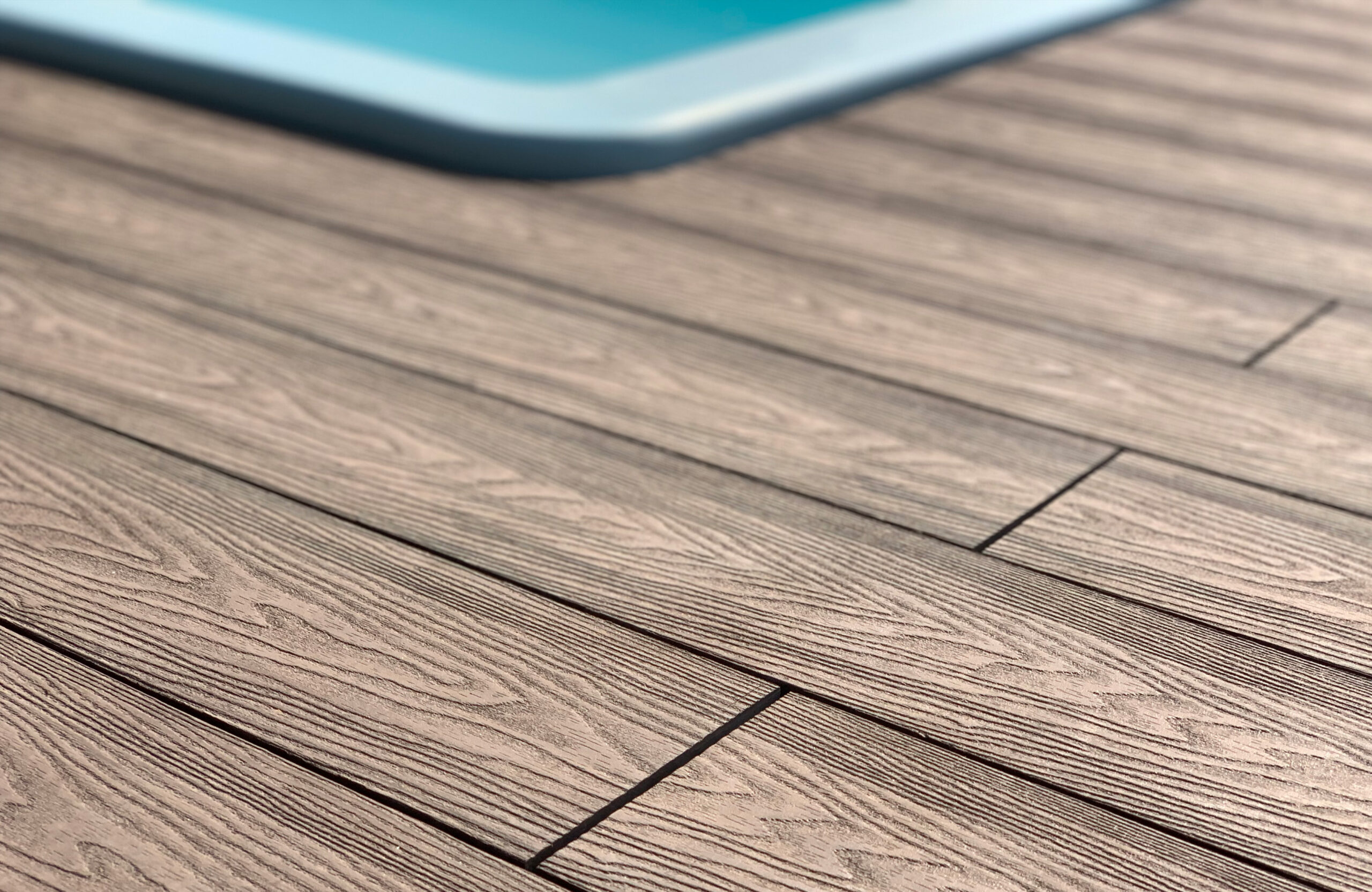 Detailed texture of Bruggan Elegant Wine Brown terrace boards installed around an outdoor swimming pool