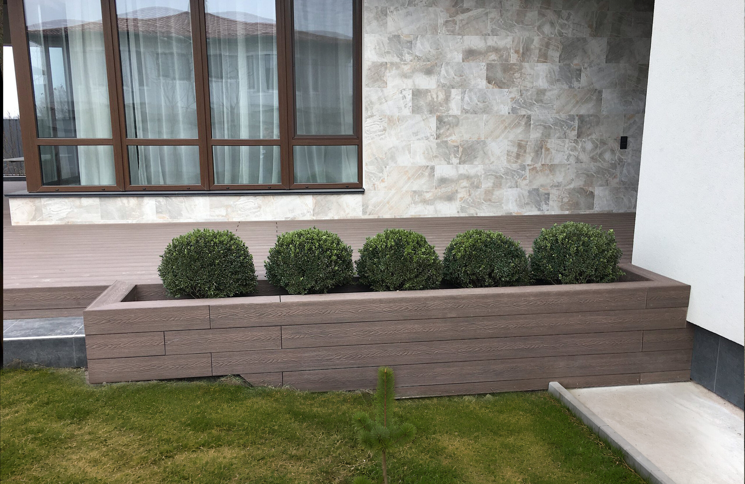 Garden planter clad with Bruggan Elegant Wine Brown composite boards beside a modern house terrace