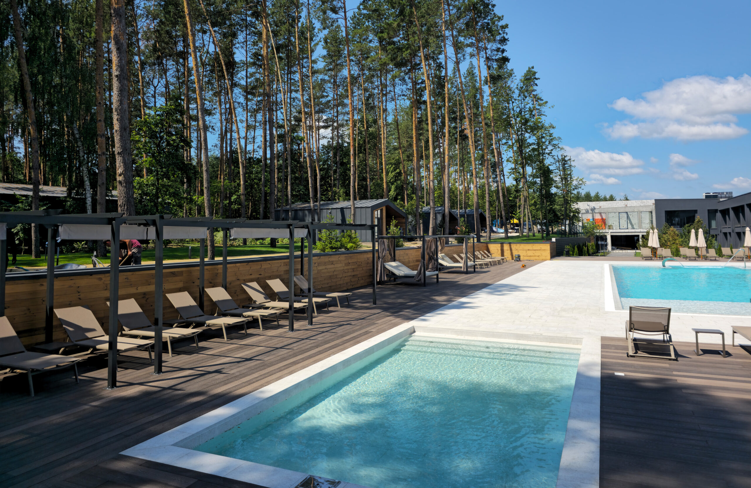 Outdoor swimming pools with Bruggan Elegant Wine Brown decking and lounge area at Riverwood Relax Park, Ukraine