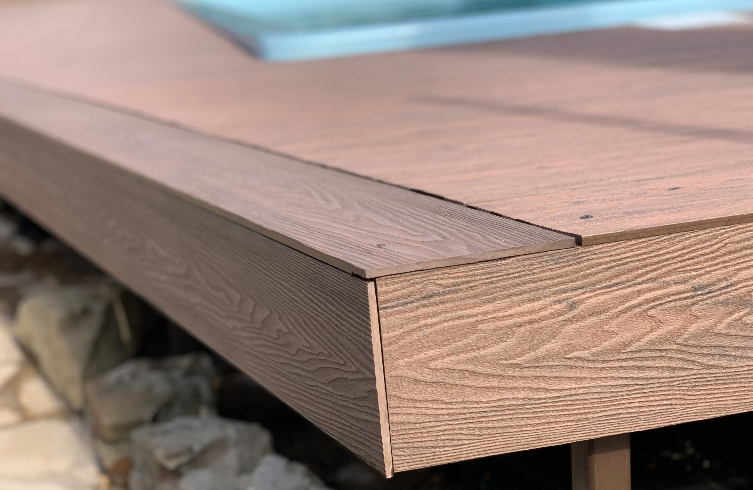Detailed view of Bruggan Elegant Wine Brown composite decking edge and fascia finish beside the swimming pool