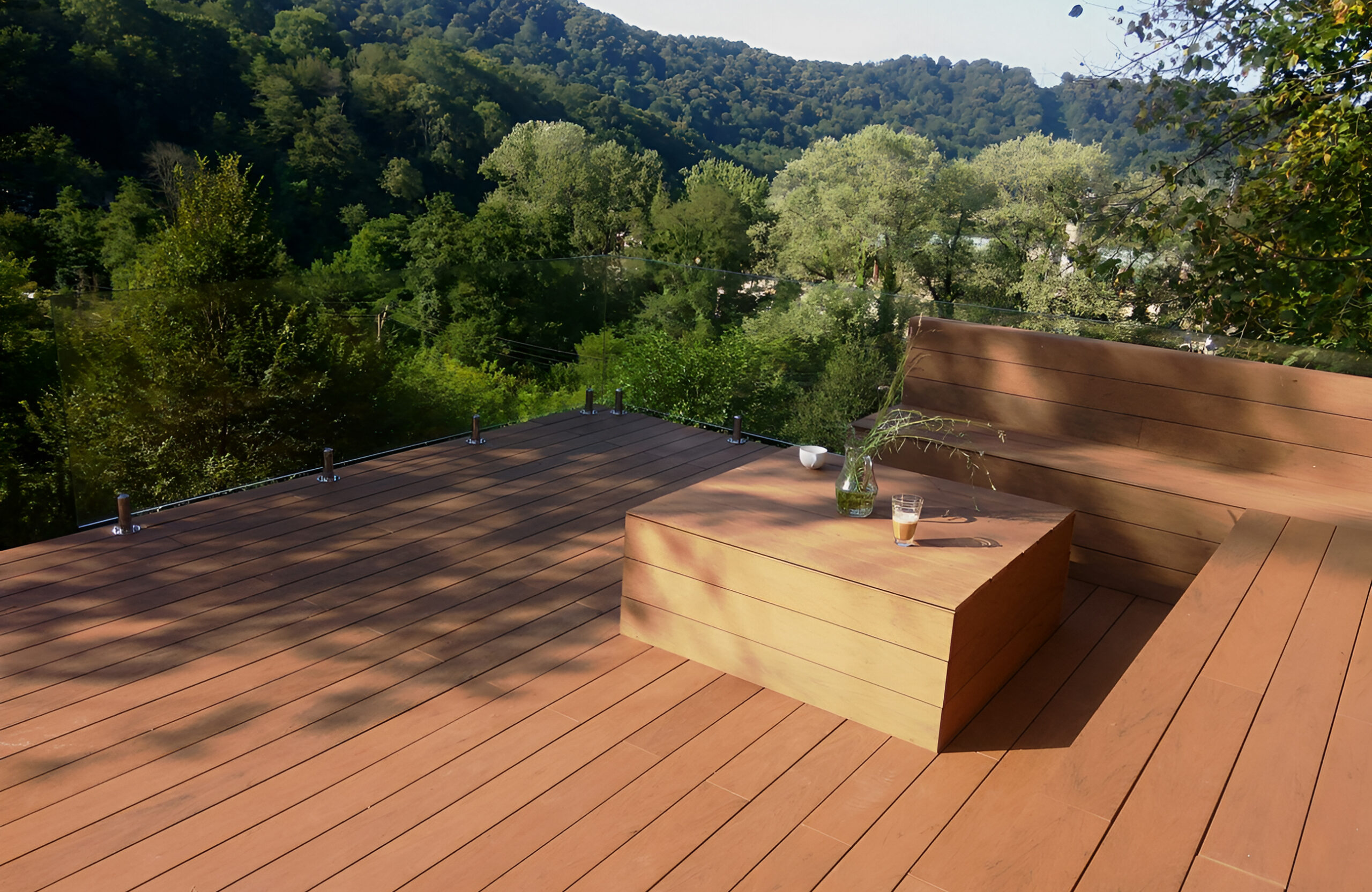 Bruggan Multicolor Cedar composite decking terrace with built-in seating overlooking a forested mountain landscape