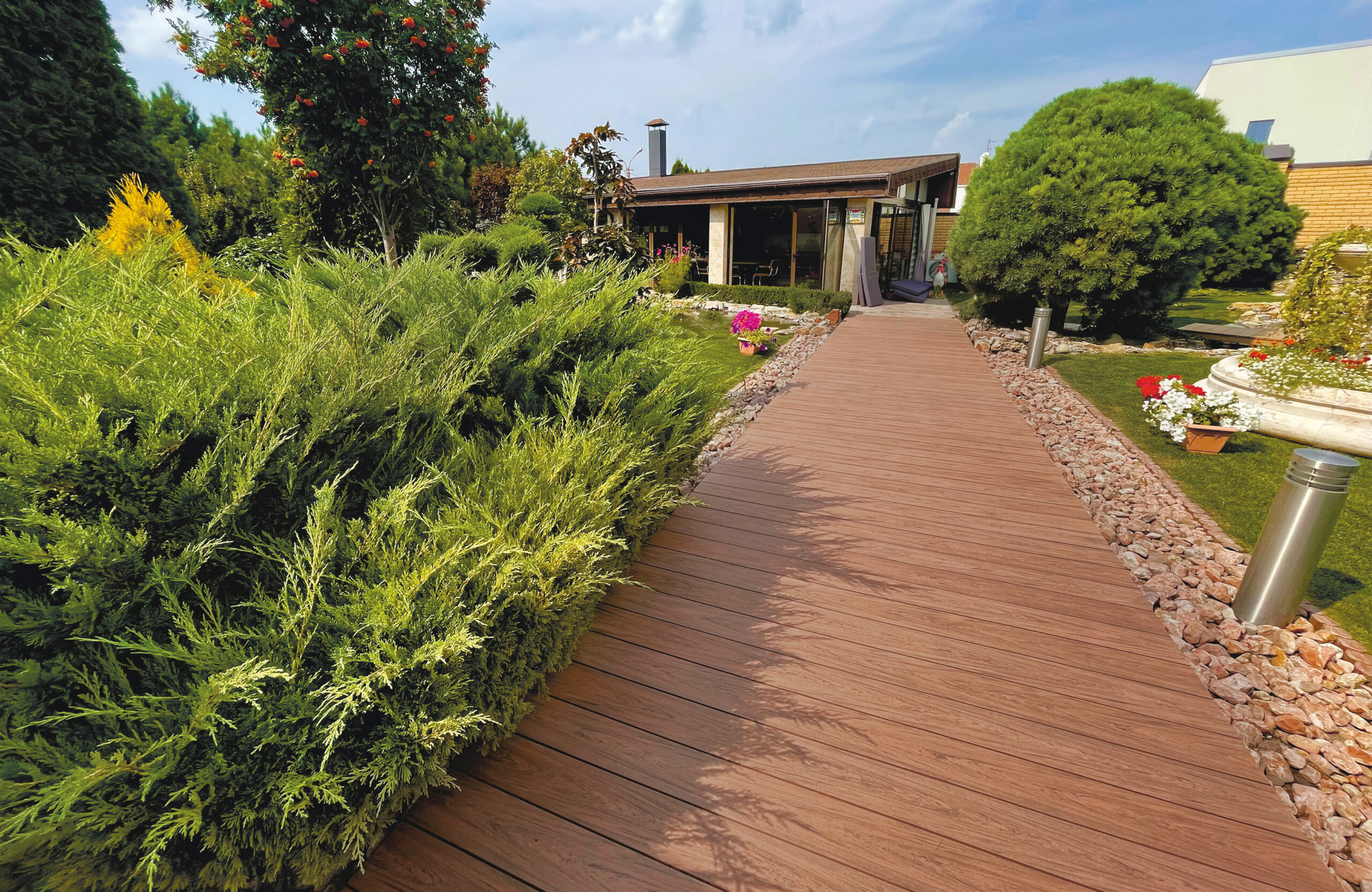 Bruggan Multicolor Cedar composite decking walkway through a landscaped garden
