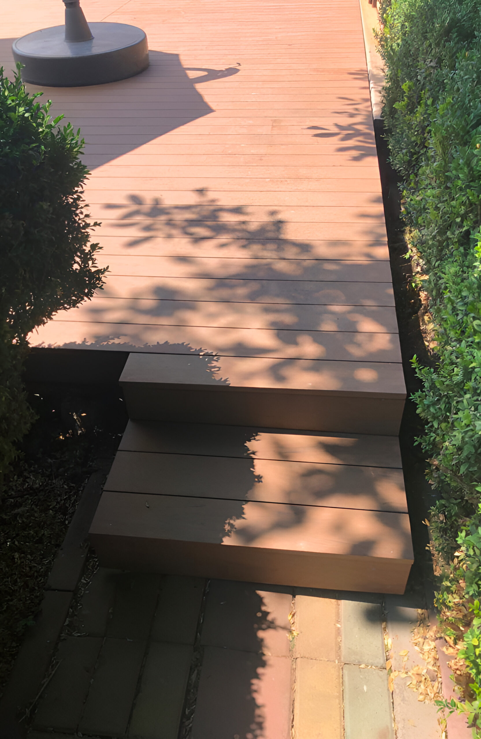 Bruggan Multicolor Cedar composite decking with steps in a landscaped garden