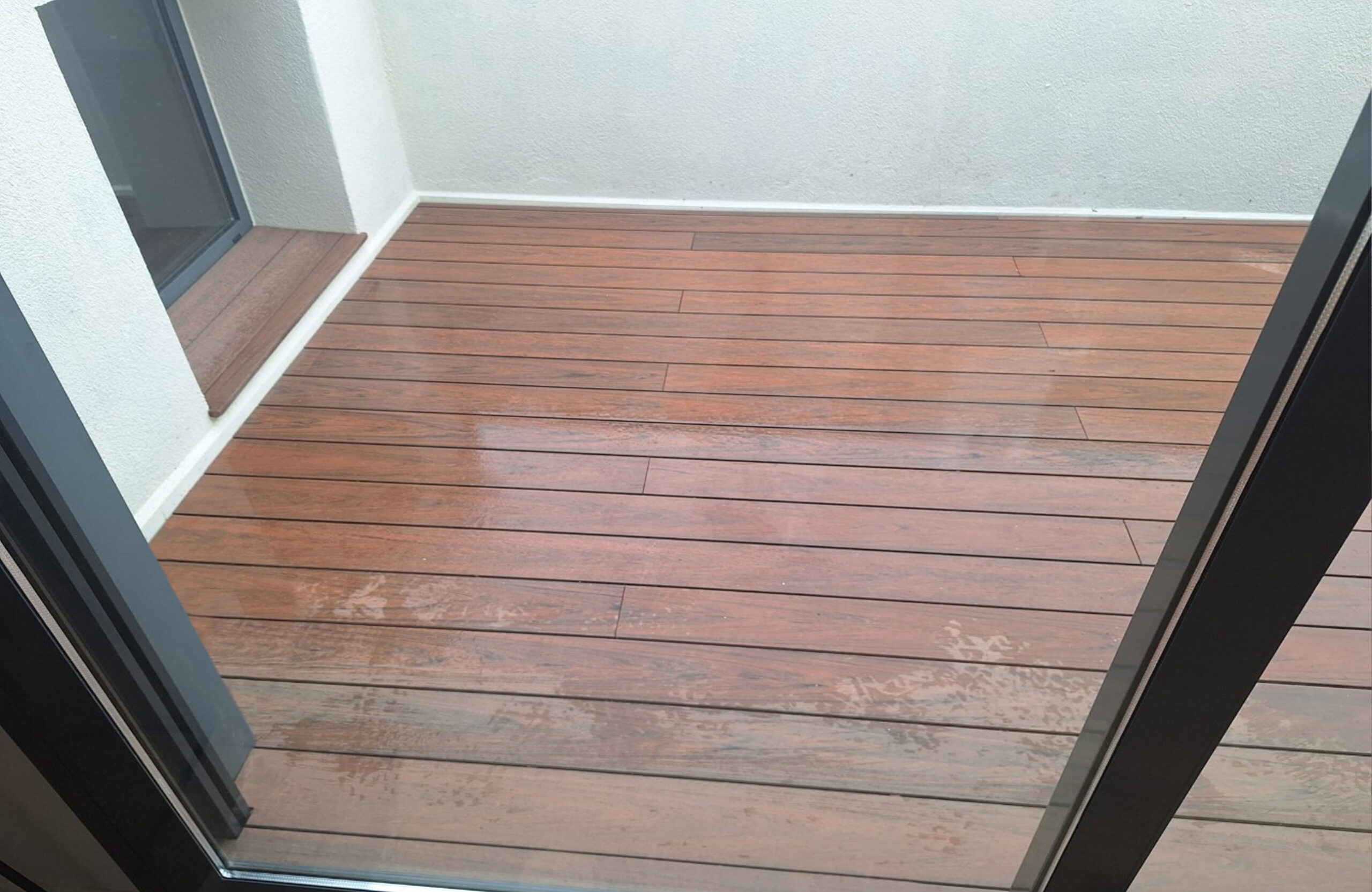 Close-up of Bruggan Multicolor Cedar composite decking on a wet outdoor terrace