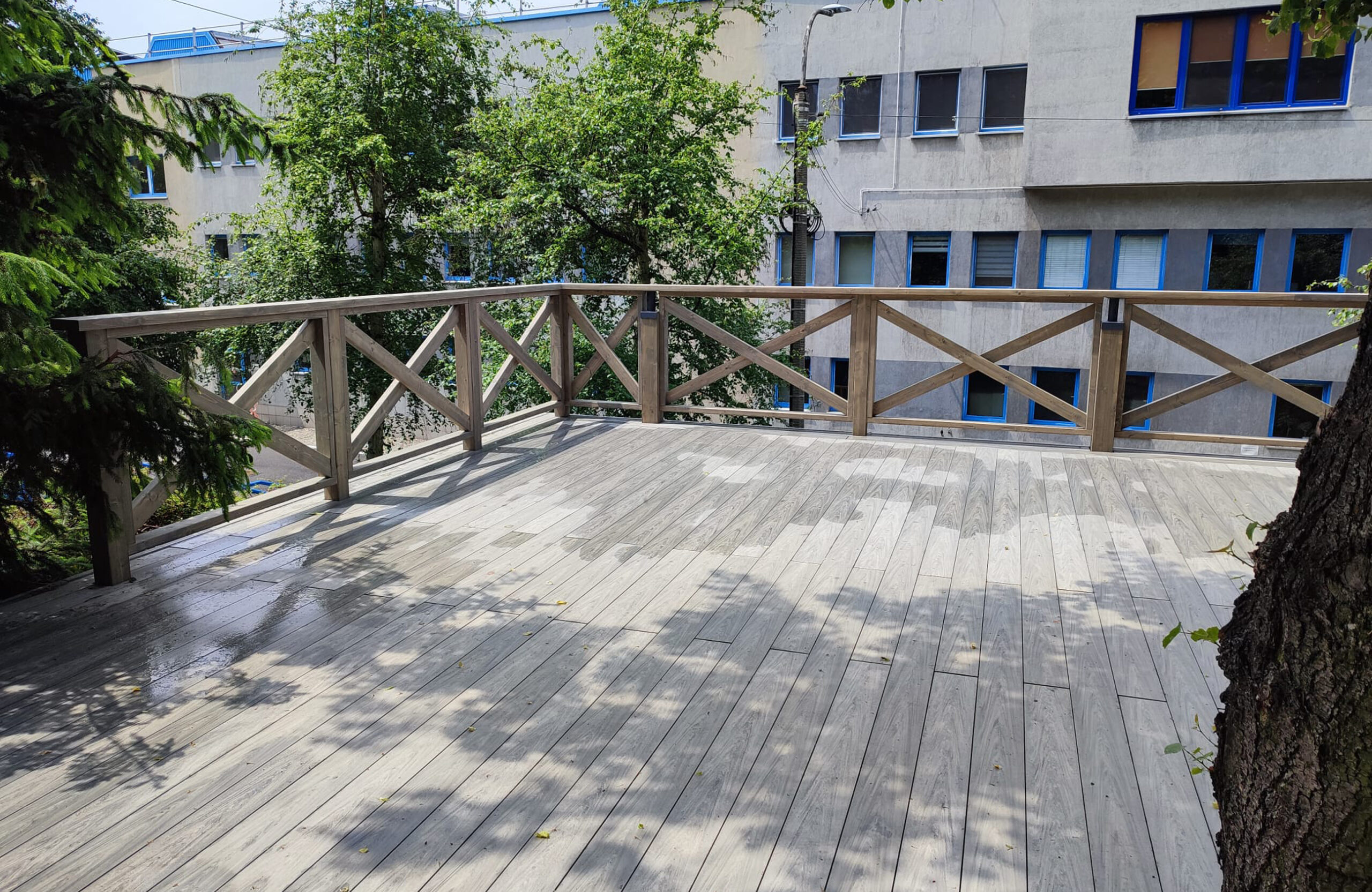 Grey BRUGGAN Multicolor composite decking installed around mature trees on a spacious outdoor