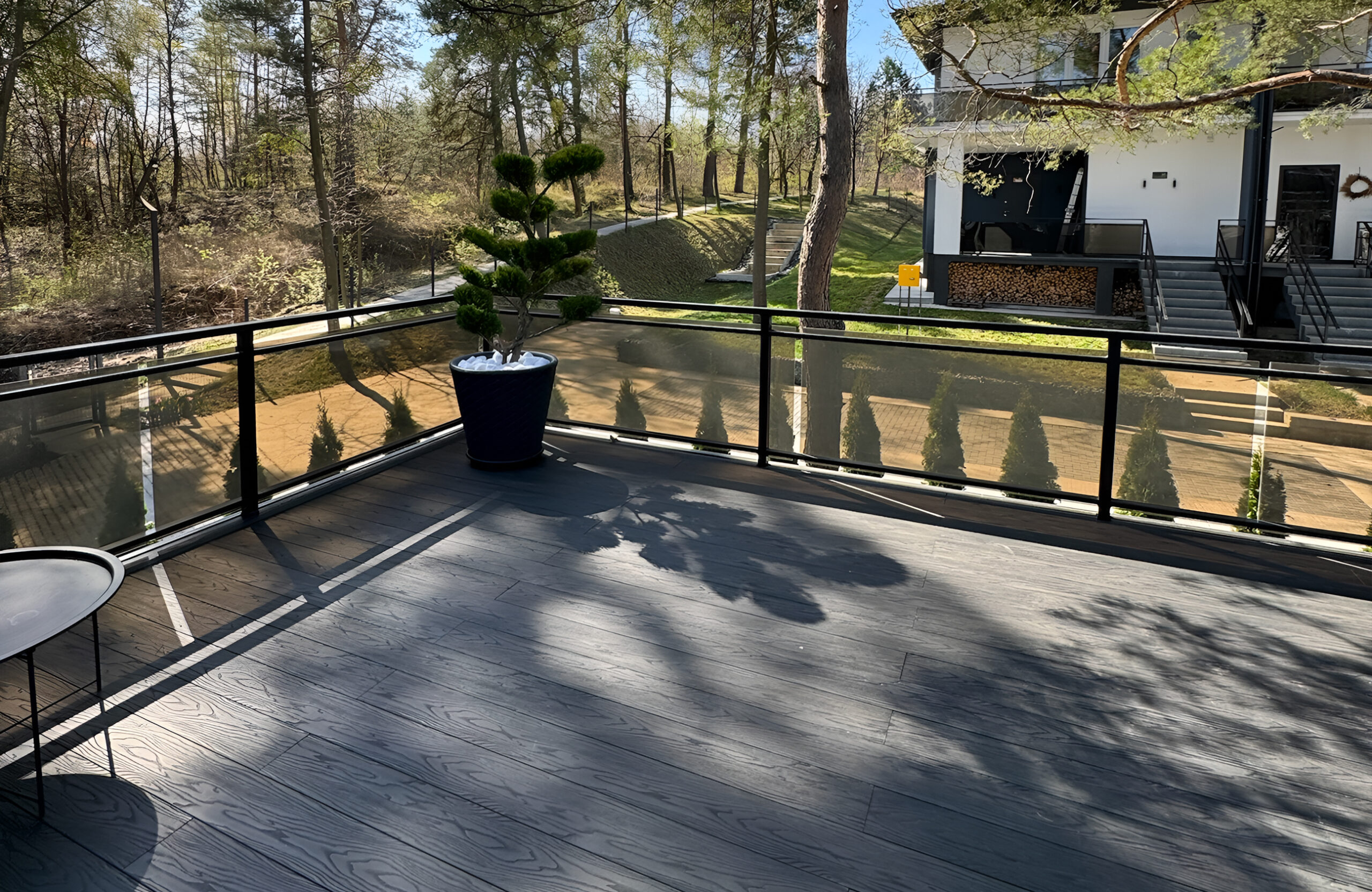 Anthracite composite decking on a modern terrace overlooking a wooded landscape