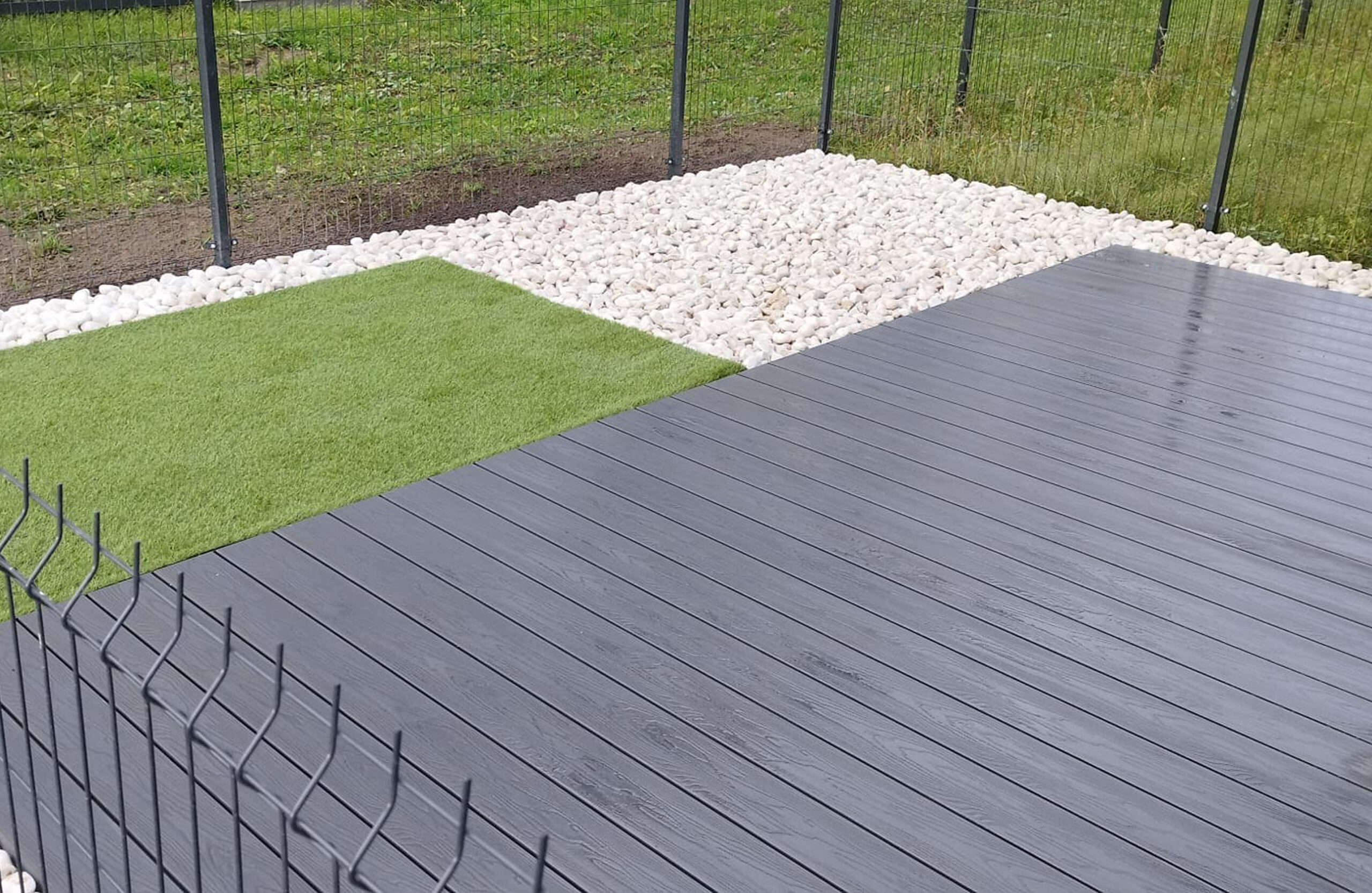 Modern terrace with Bruggan Elegant anthracite decking, artificial grass and white stones