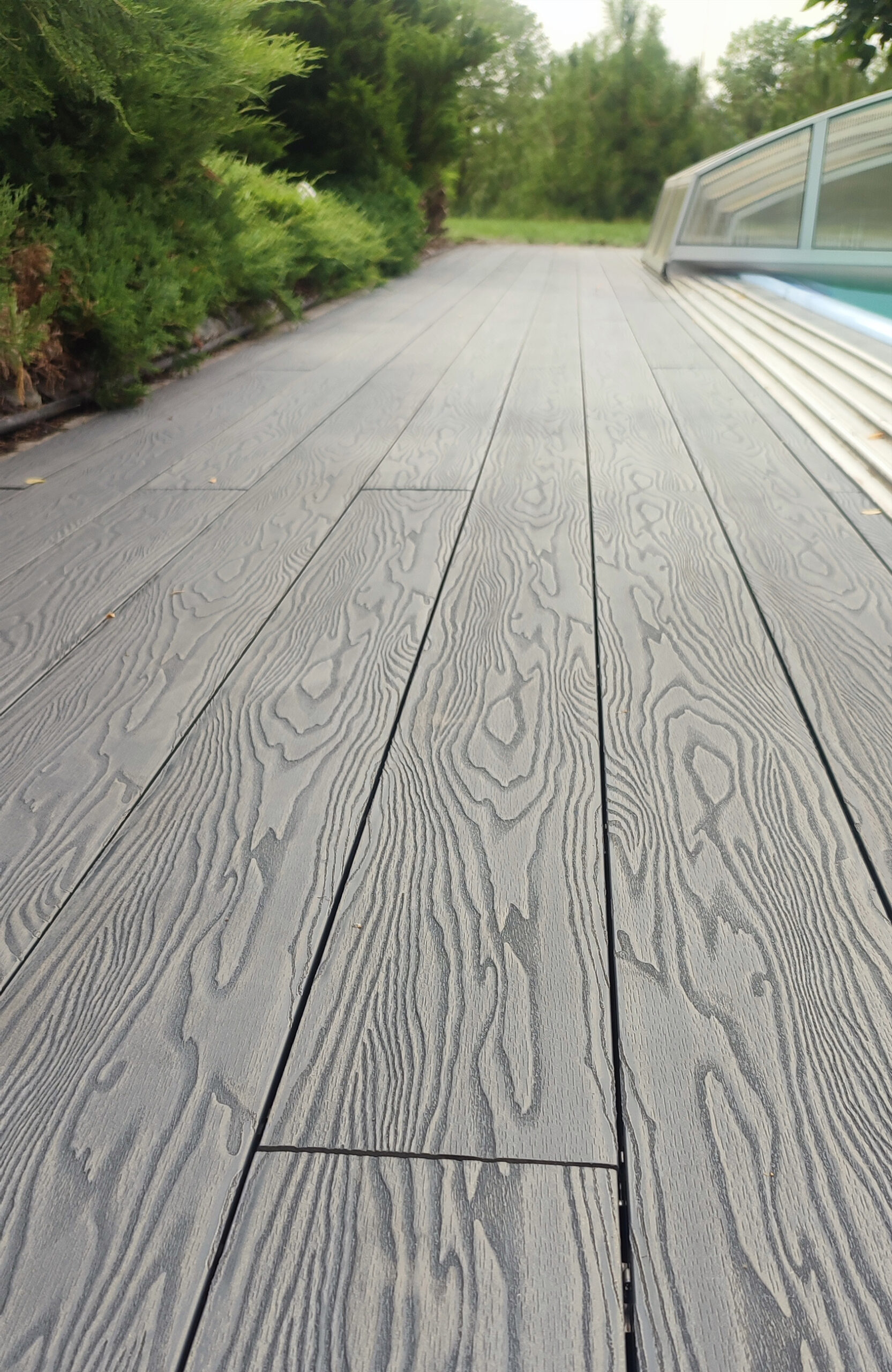 Close-up of Bruggan Elegant Anthracite decking with natural wood grain texture beside a swimming pool