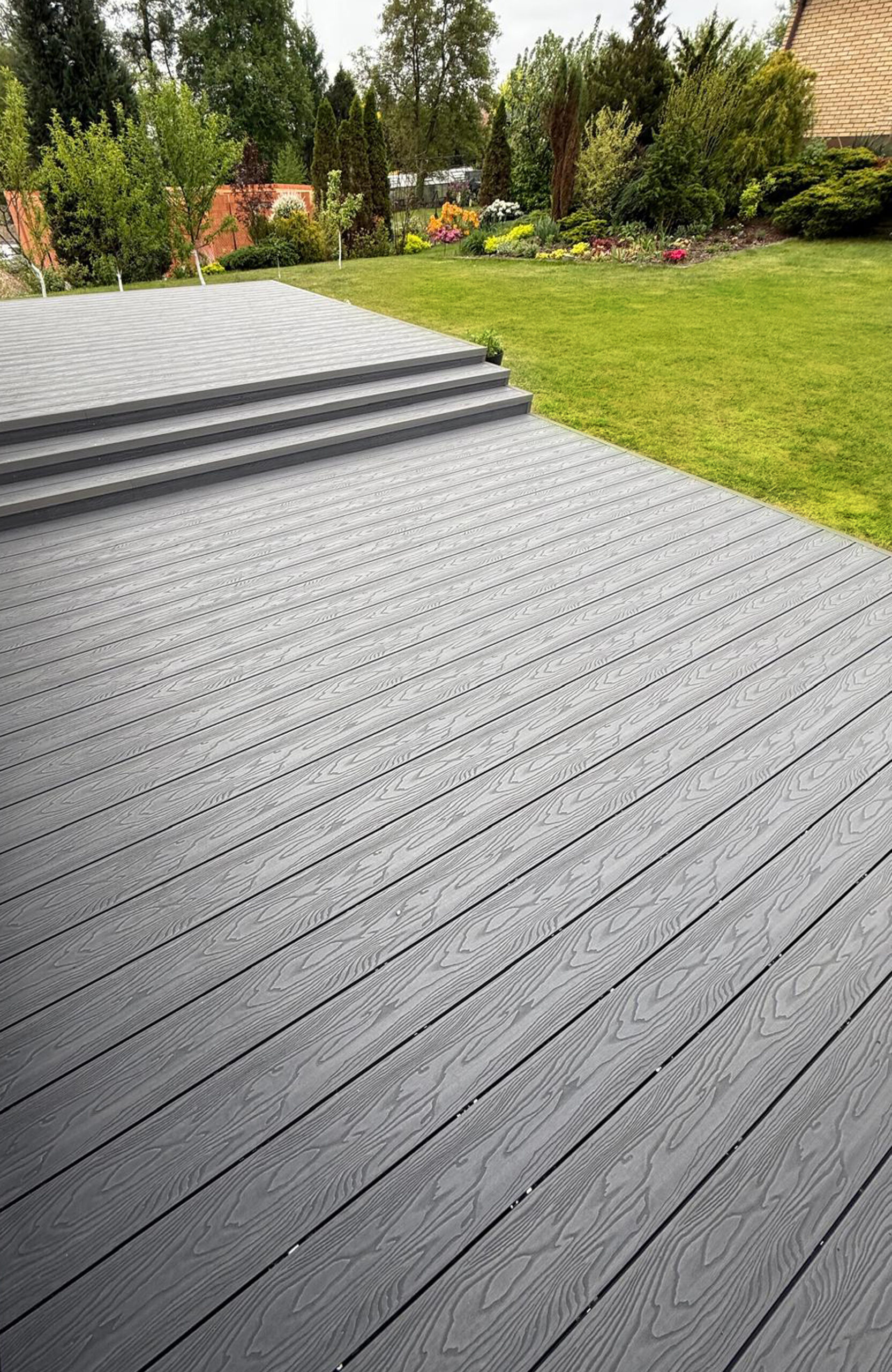 Bruggan Elegant Graphite decking with natural wood grain texture overlooking a landscaped garden