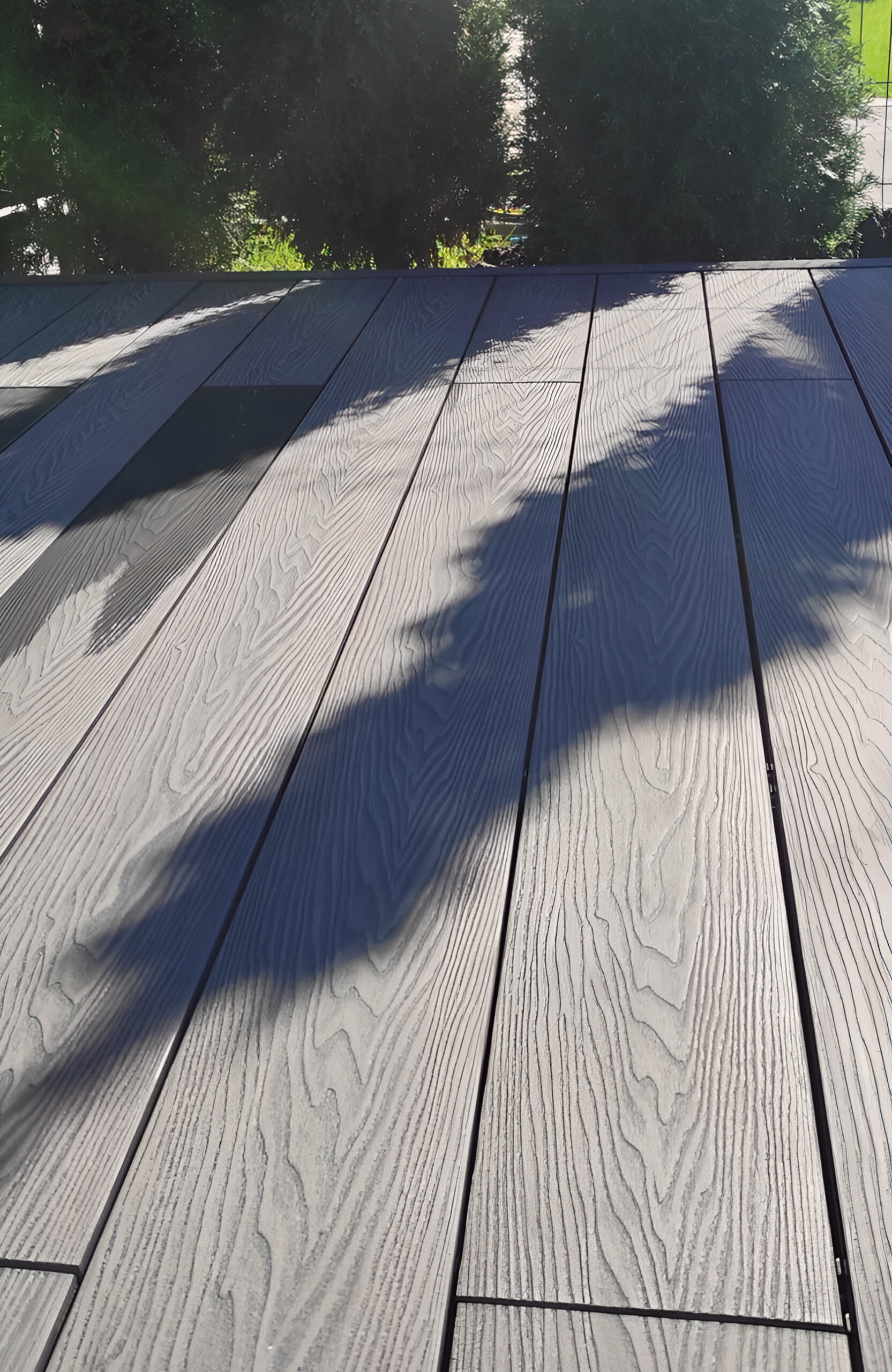 Close-up of Bruggan Elegant Graphite decking with natural wood grain texture in sunlight
