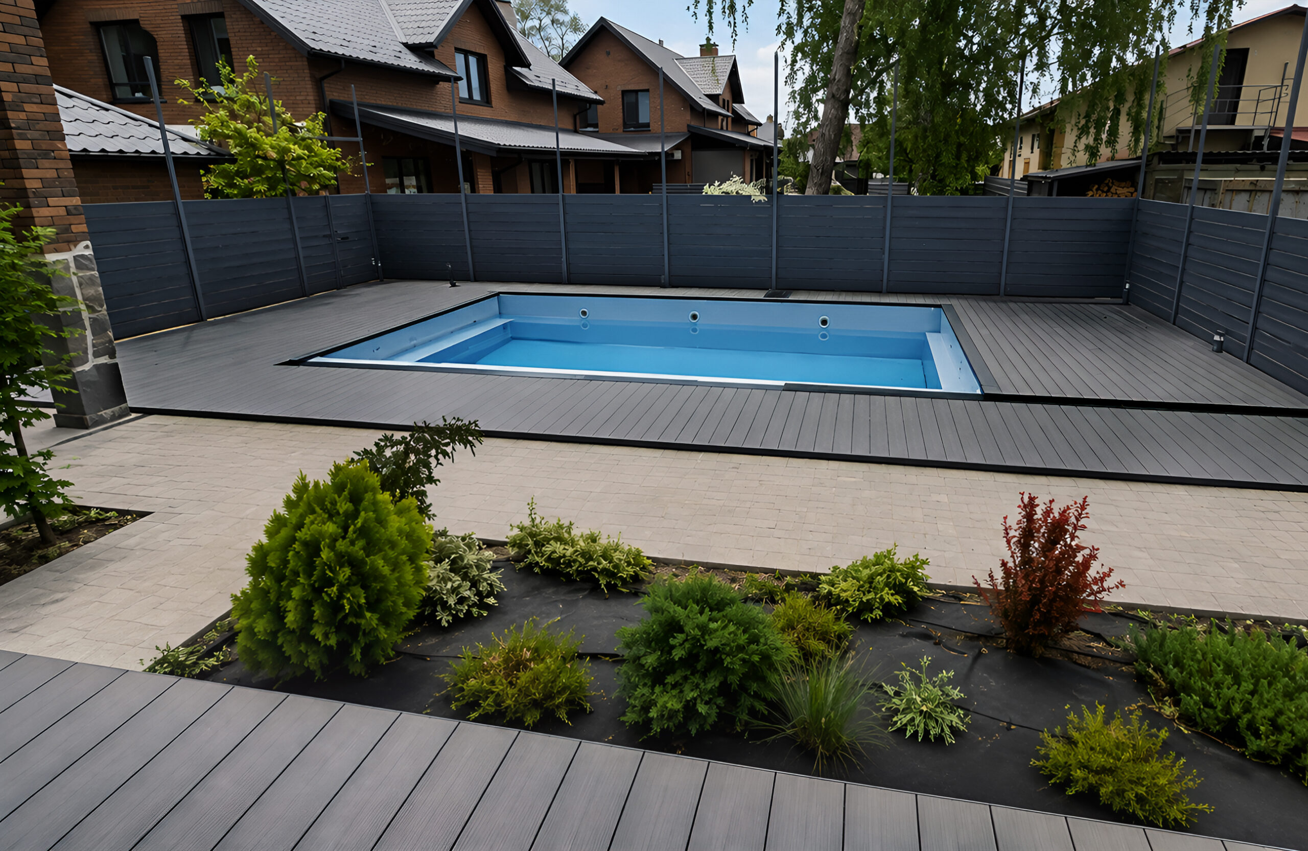 Modern backyard pool area with Bruggan Elegant Graphite composite decking and landscaped garden