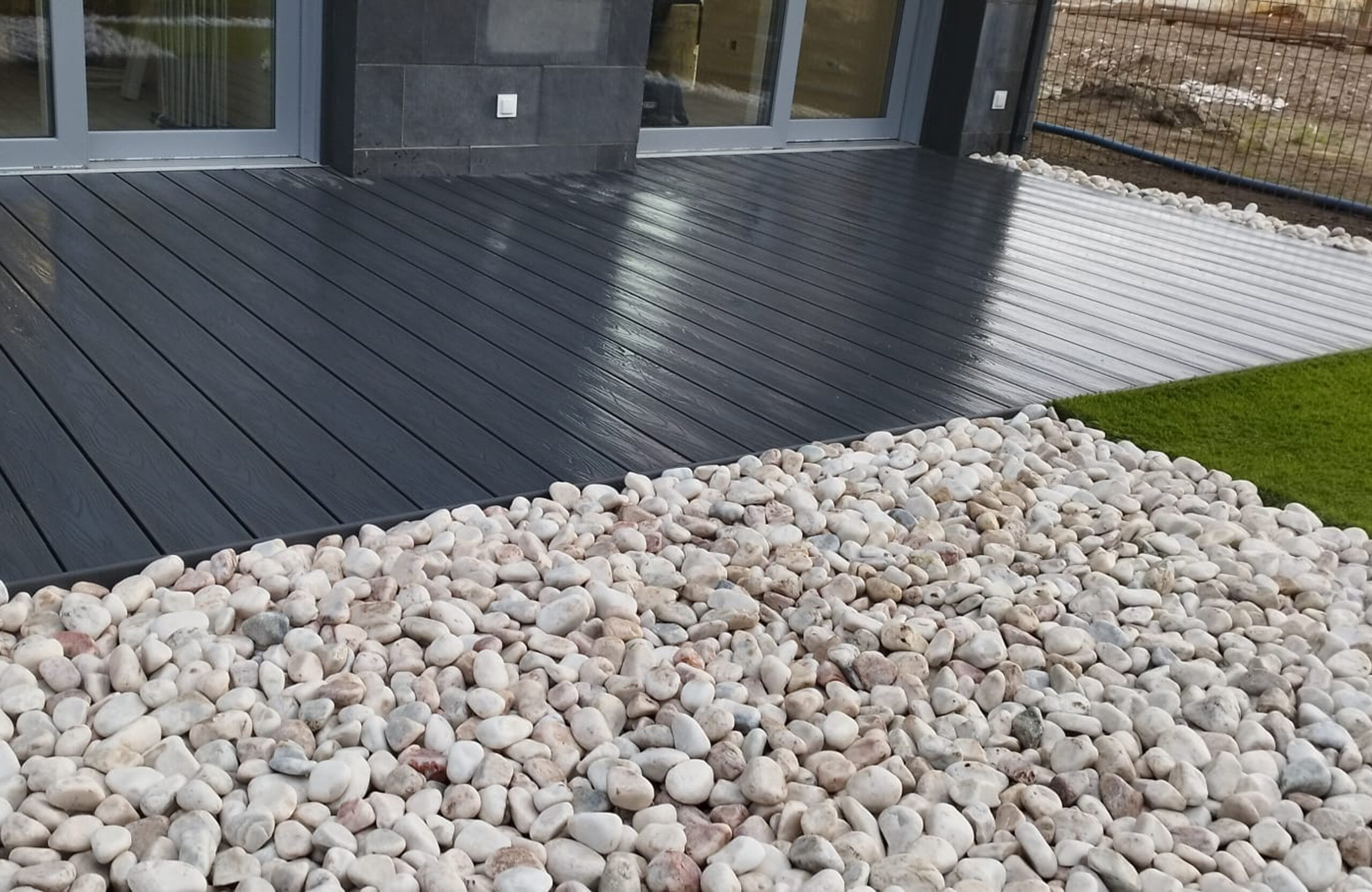 Outdoor terrace with Bruggan Elegant anthracite composite decking and decorative stone landscaping