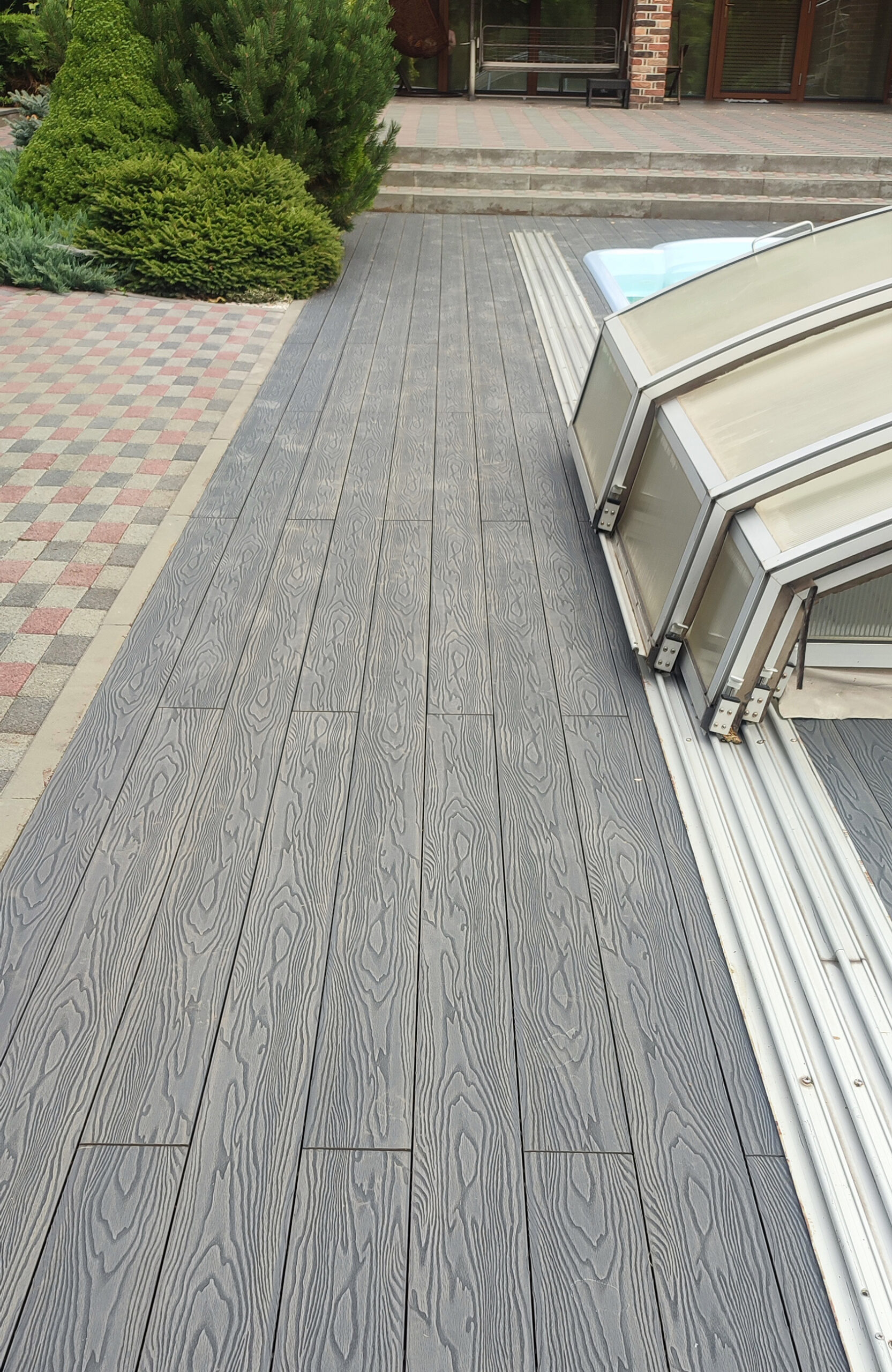 Poolside terrace with Bruggan Elegant Anthracite decking and landscaped garden