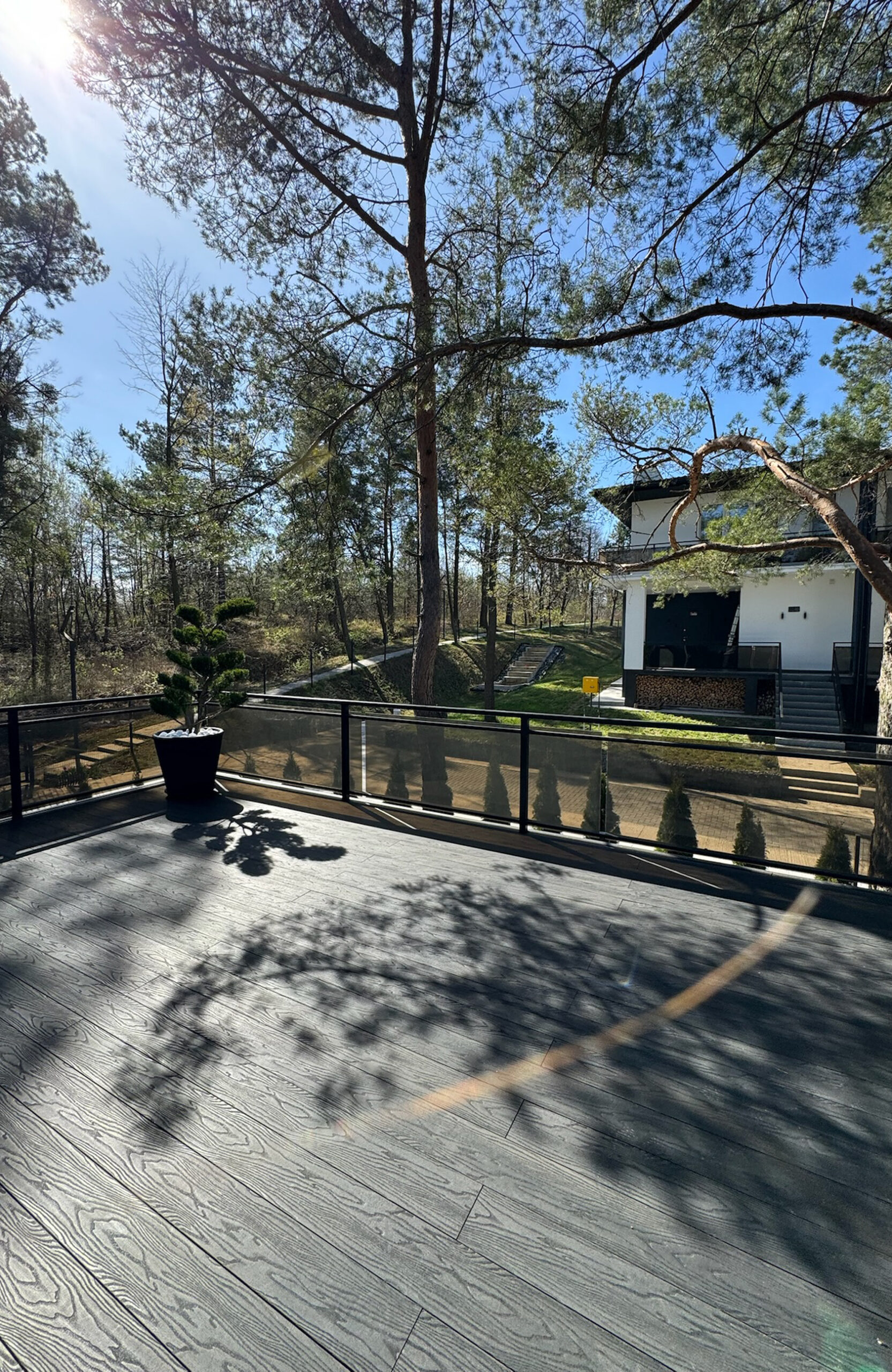 Modern outdoor terrace with anthracite composite decking surrounded by pine trees