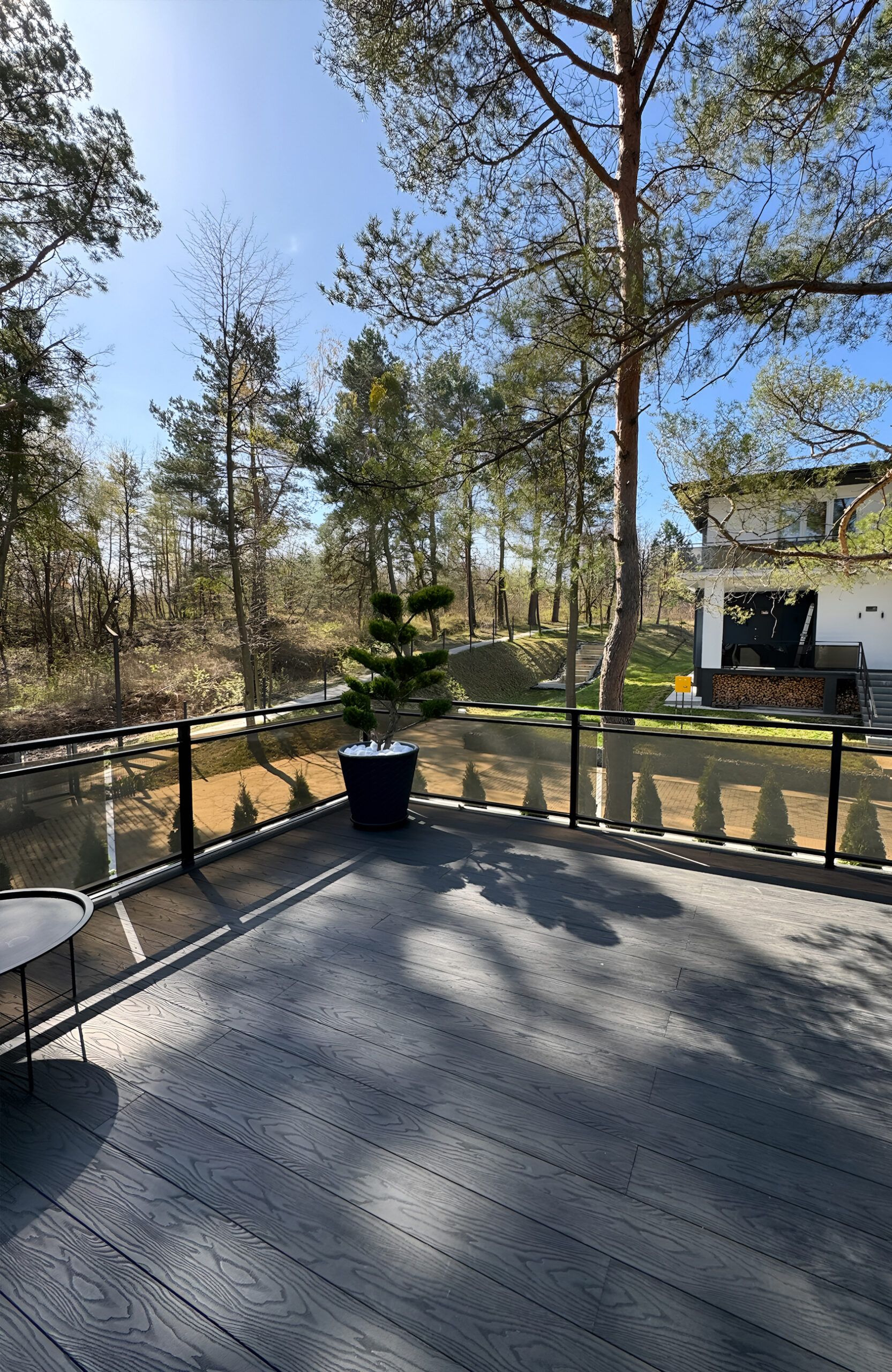 Modern outdoor terrace with anthracite composite decking surrounded by pine trees