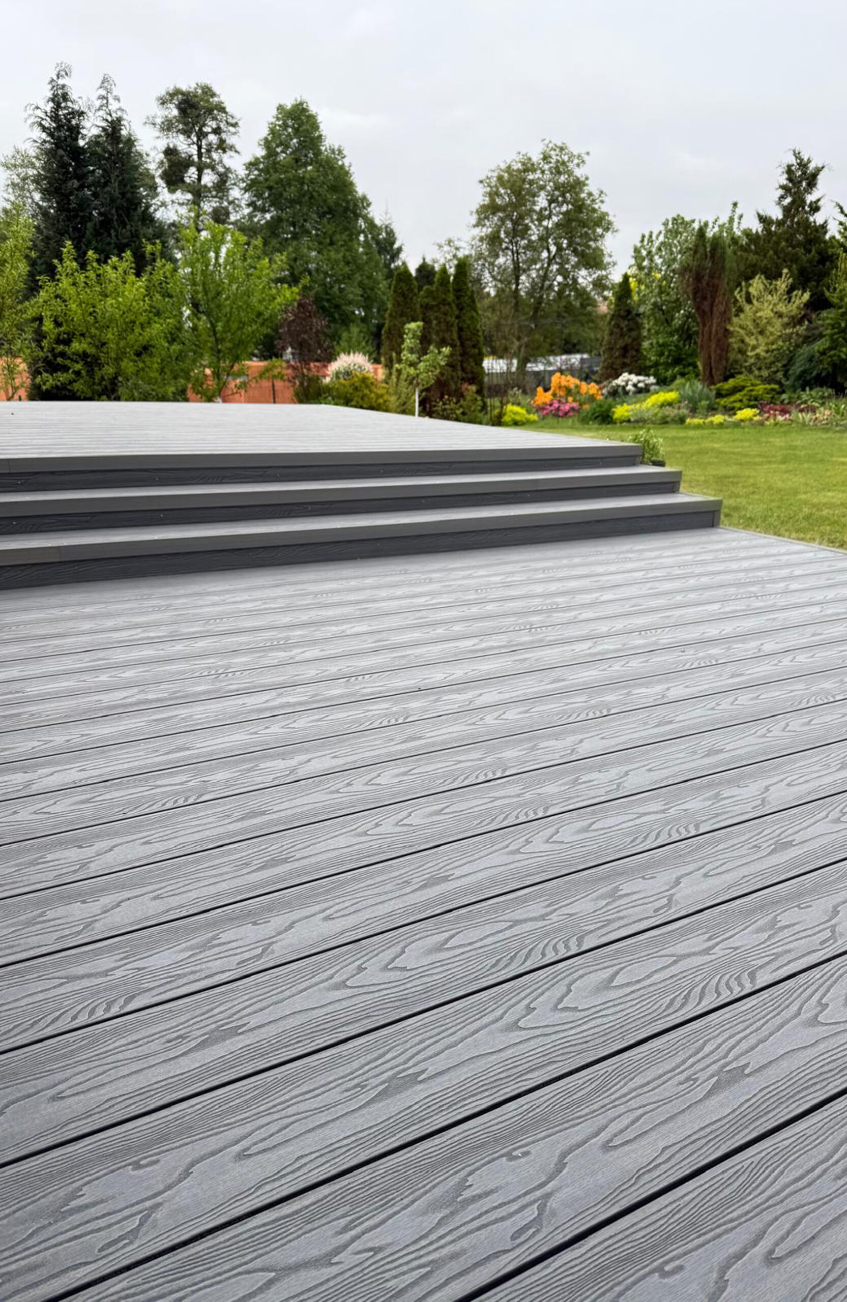 Graphite composite decking with realistic wood grain texture and garden view