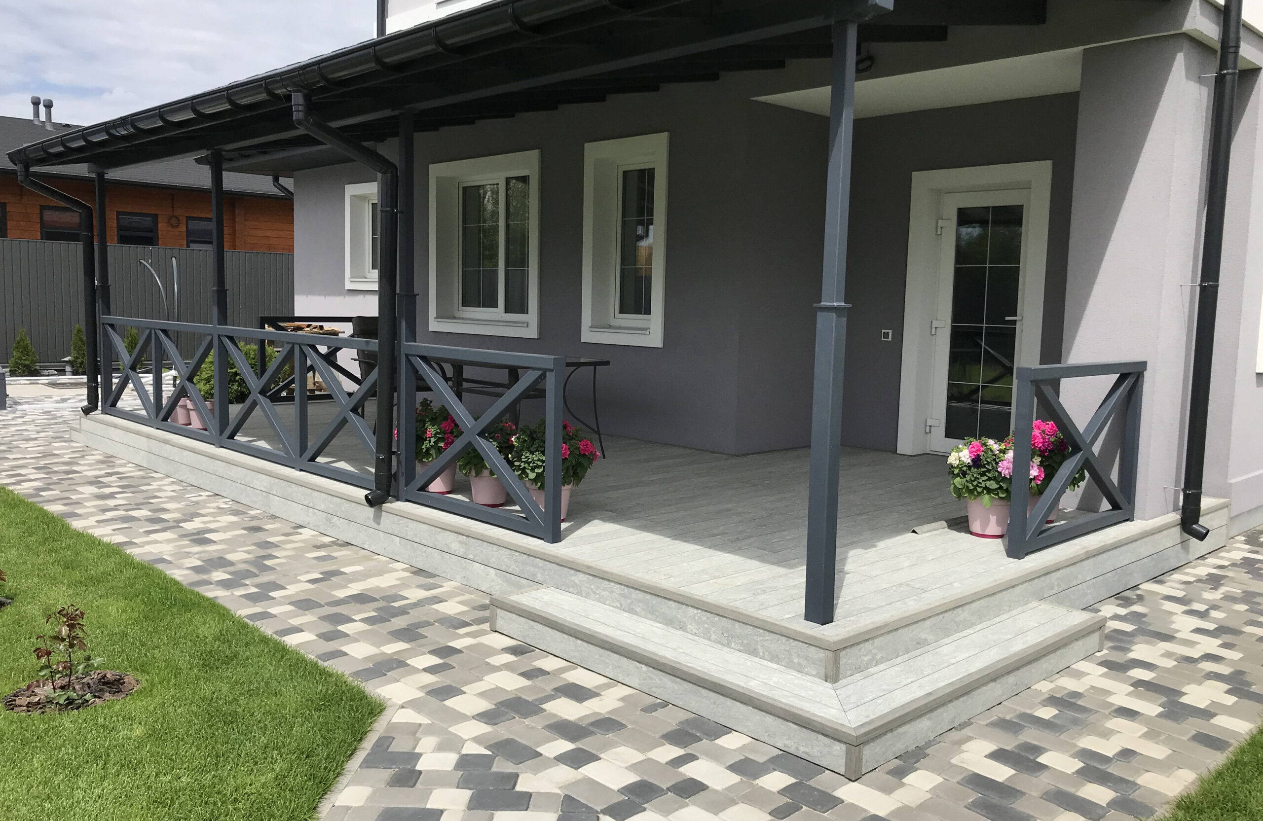 BRUGGAN Multicolor grey decking used for a stylish covered patio with integrated stairs and decorative railings.