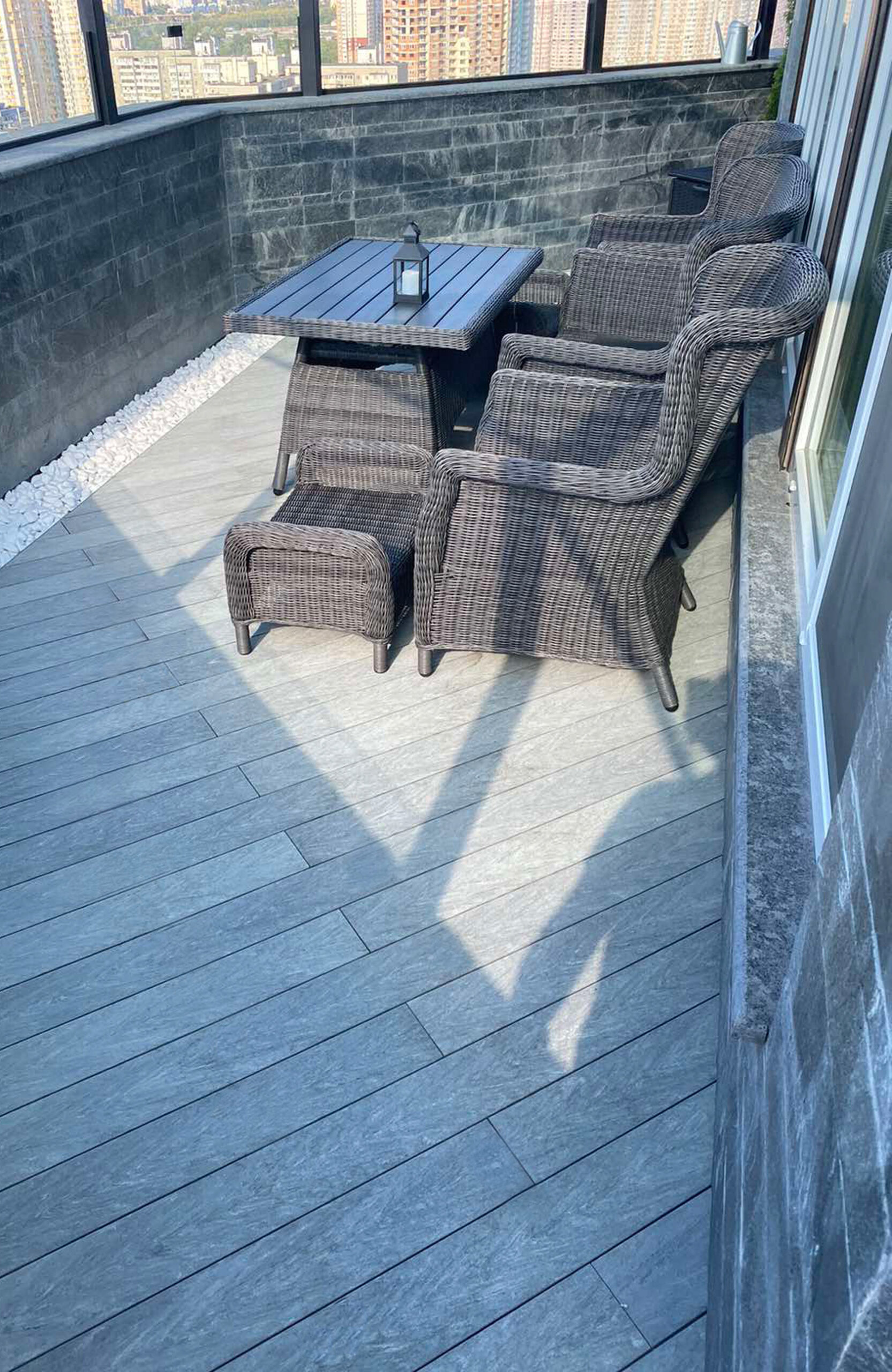 Urban balcony with BRUGGAN Multicolor grey composite decking, seating area and panoramic glazing