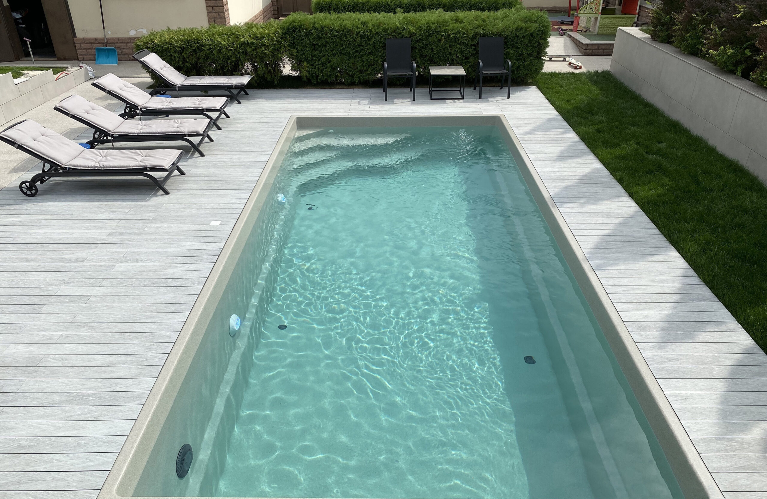 Modern pool terrace with BRUGGAN Multicolor grey decking and sun loungers