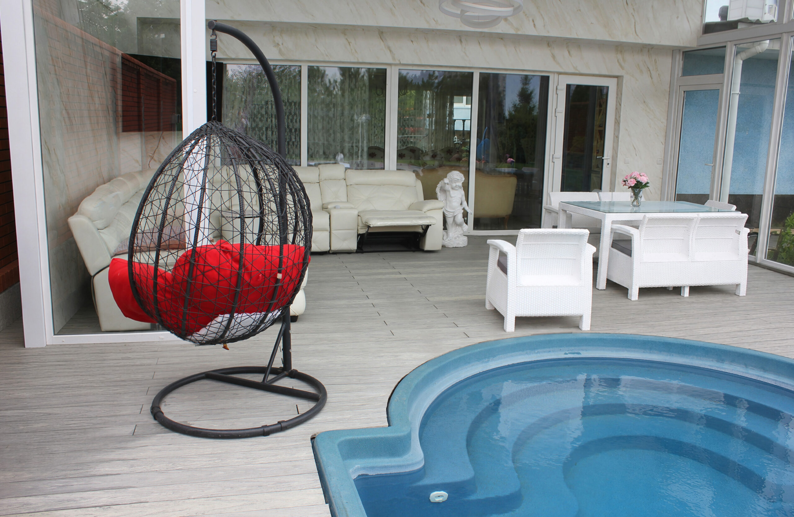 BRUGGAN Multicolor grey composite decking around a private outdoor swimming pool with a covered lounge area and garden