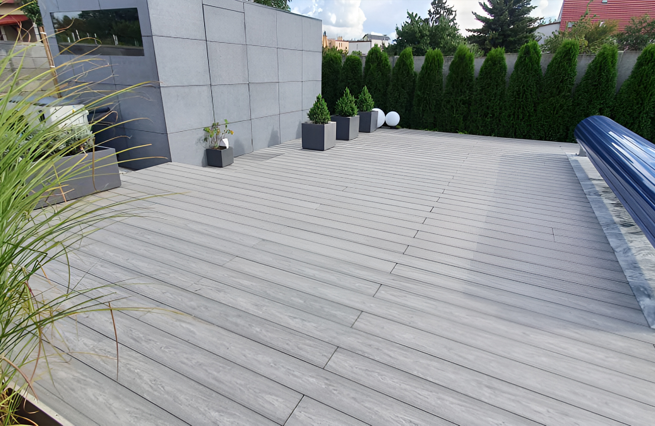 BRUGGAN Multicolor grey composite decking around a modern outdoor swimming pool and terrace in a landscaped private garden