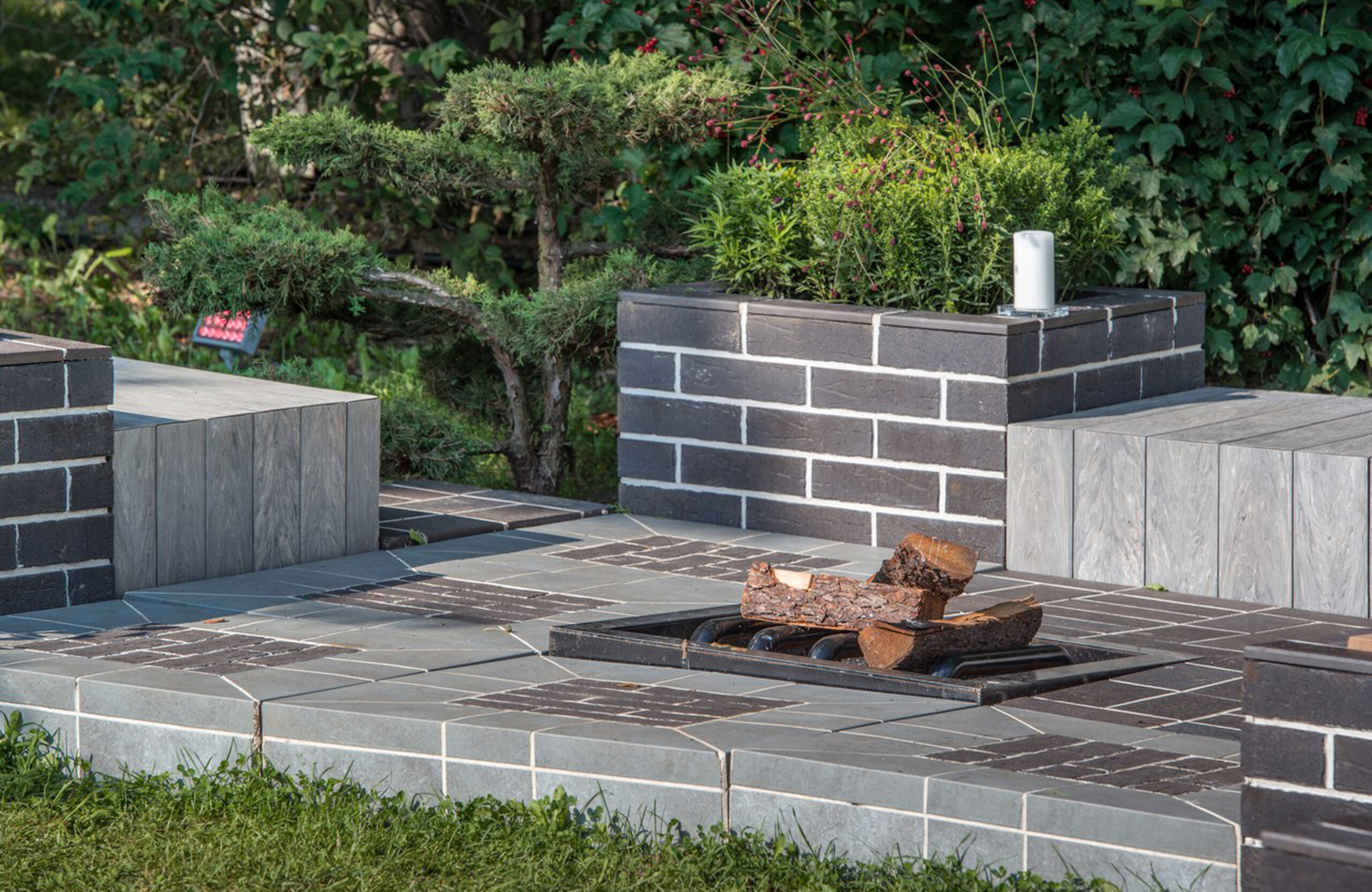 Landscaped outdoor area with BRUGGAN Multicolor grey composite decking, lush plants, rocks and water features