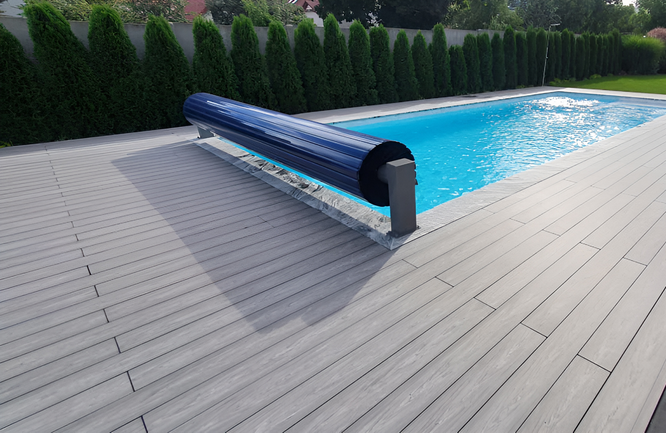 BRUGGAN Multicolor grey composite decking around a modern outdoor swimming pool and terrace in a landscaped private garden
