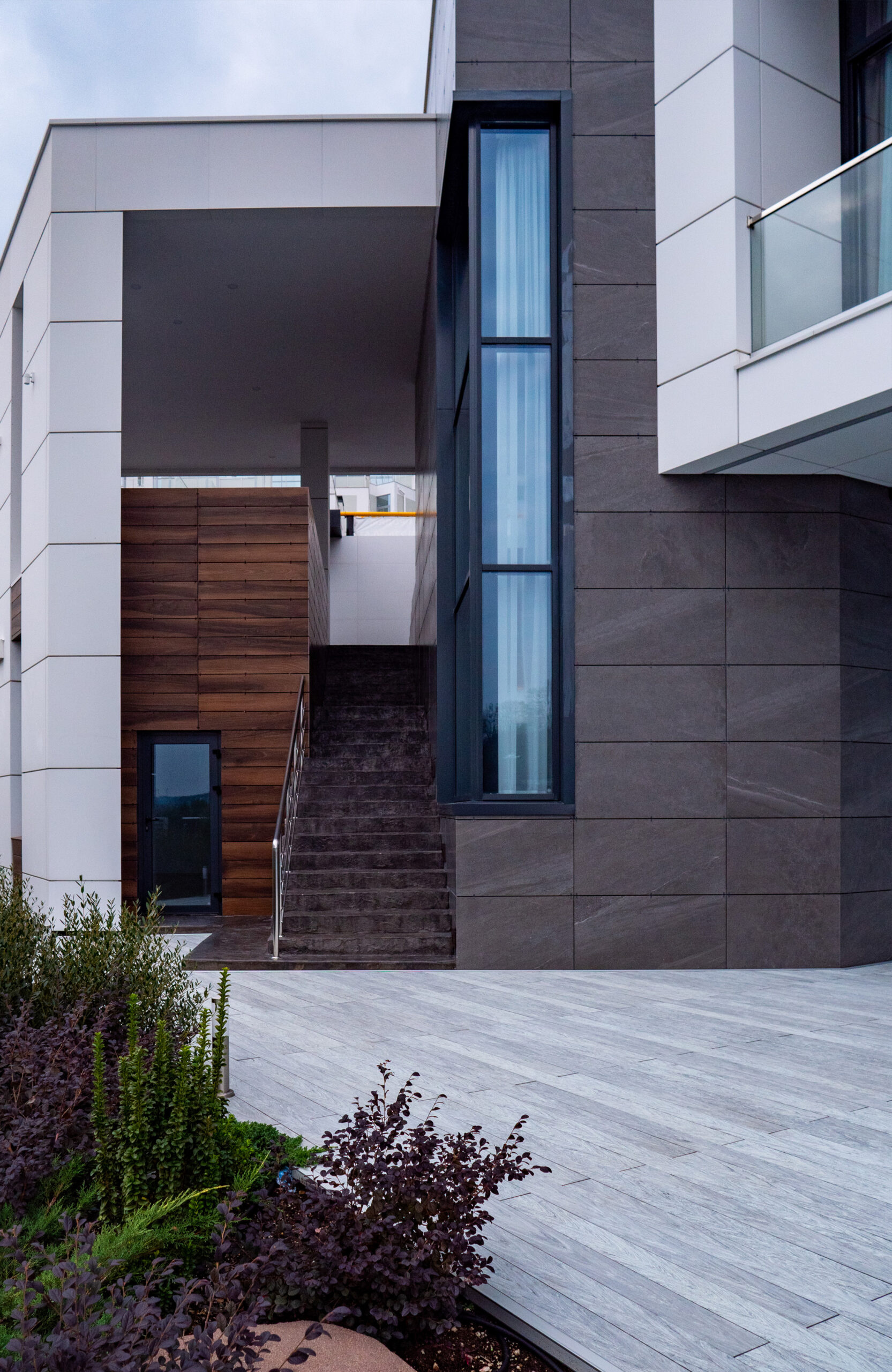 Grey composite decking terrace beside a modern house with landscaped garden
