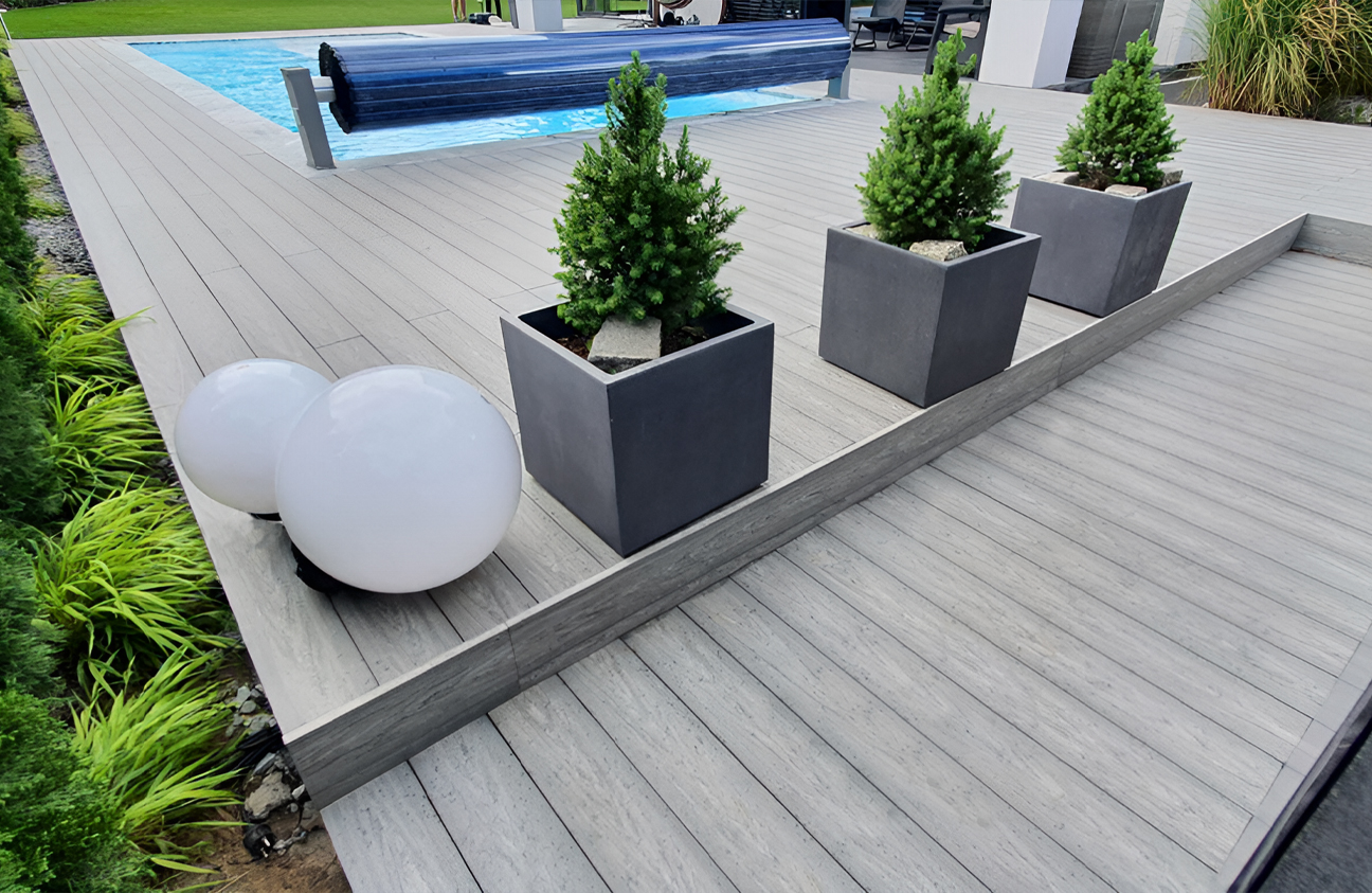 BRUGGAN Multicolor grey composite decking around a modern outdoor swimming pool and terrace in a landscaped private garden
