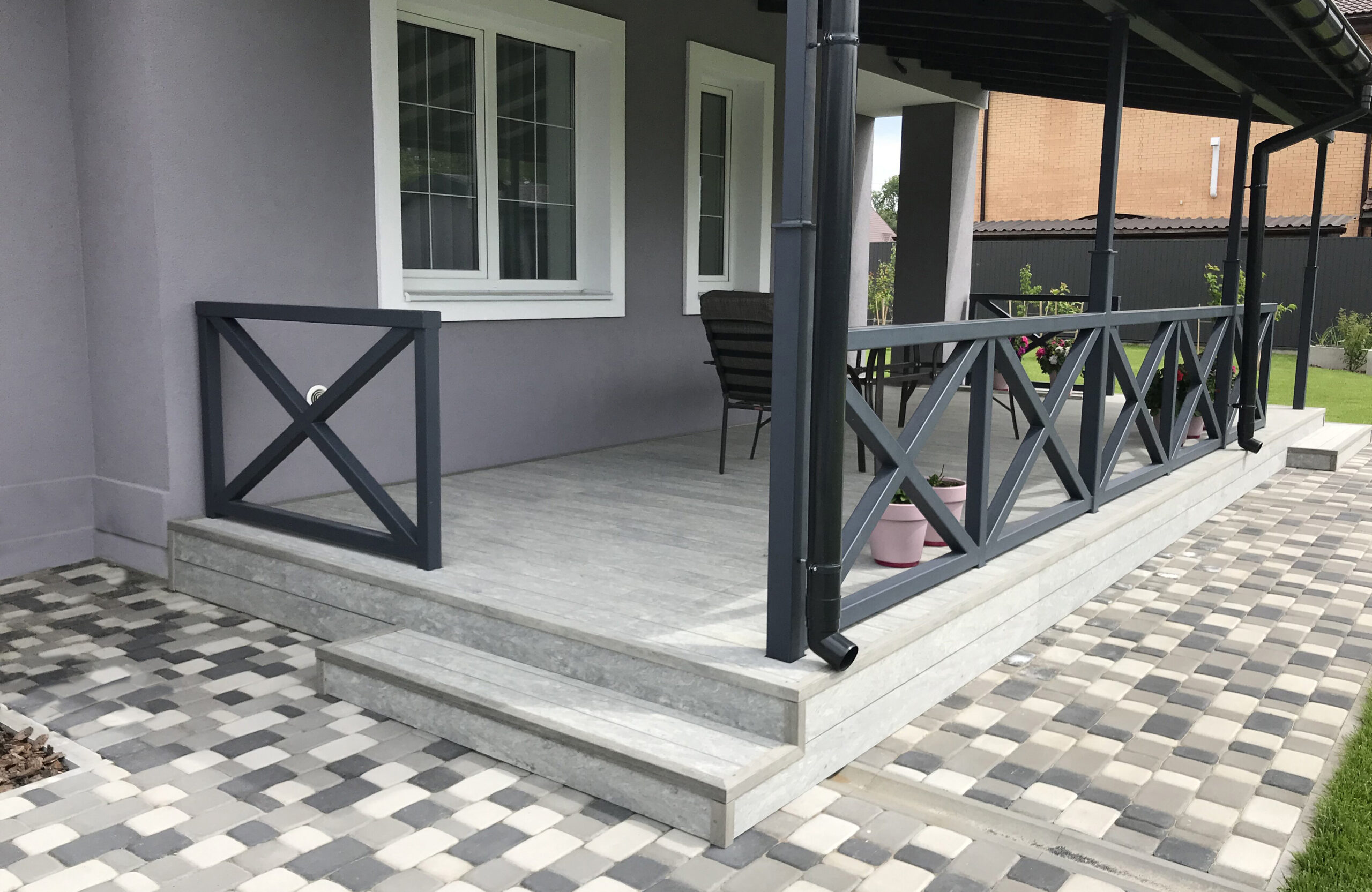 BRUGGAN Multicolor grey decking used for a stylish covered patio with integrated stairs and decorative railings.